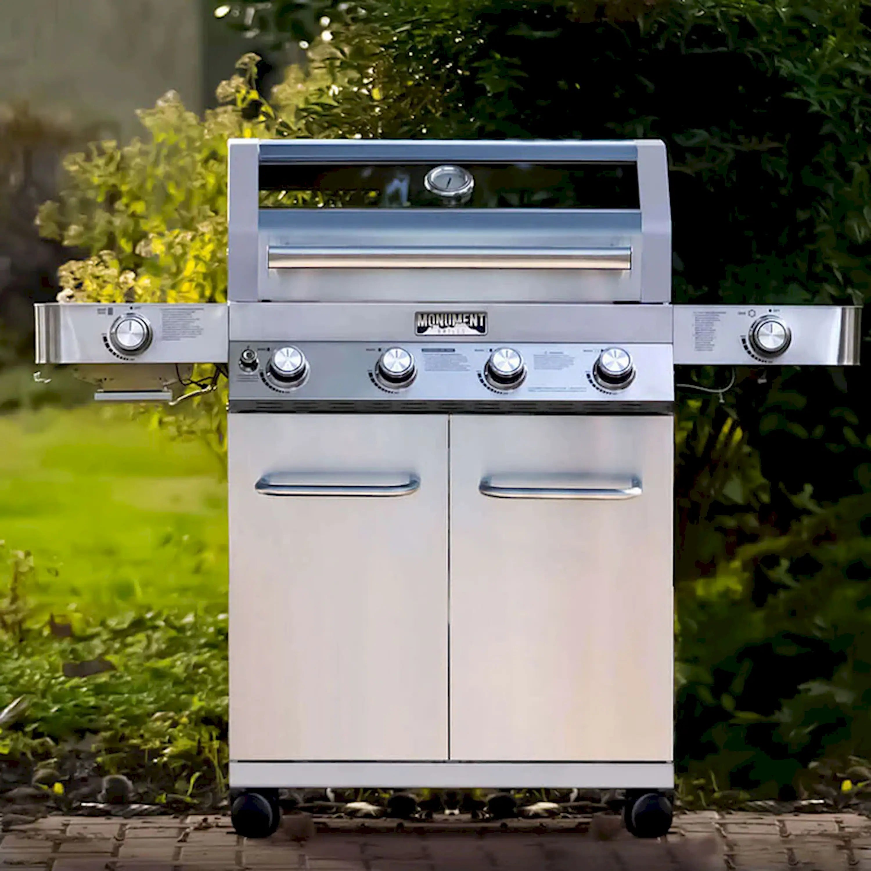 Stainless steel propane grill with four burner control knobs and cabinet doors