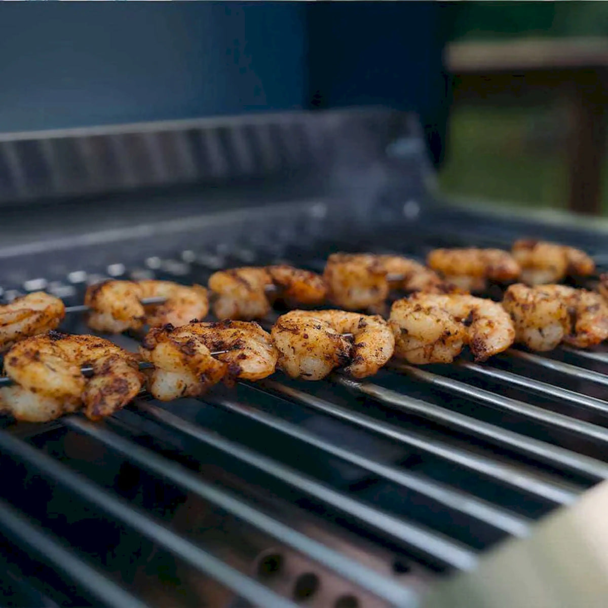 Tabletop propane grill grate with searing burgers and rising smoke
