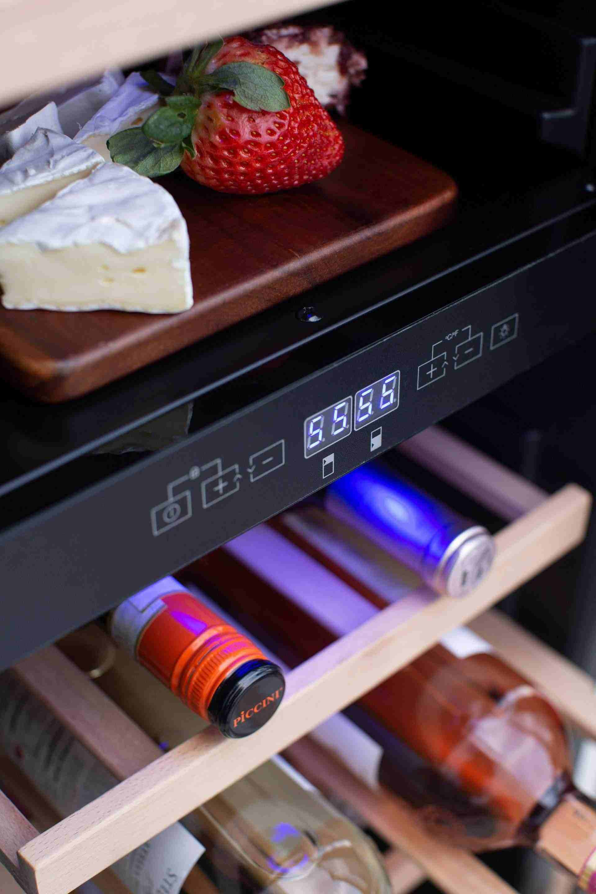Wine cooler interior close-up with fruit on top shelf and bottles on lower shelf
