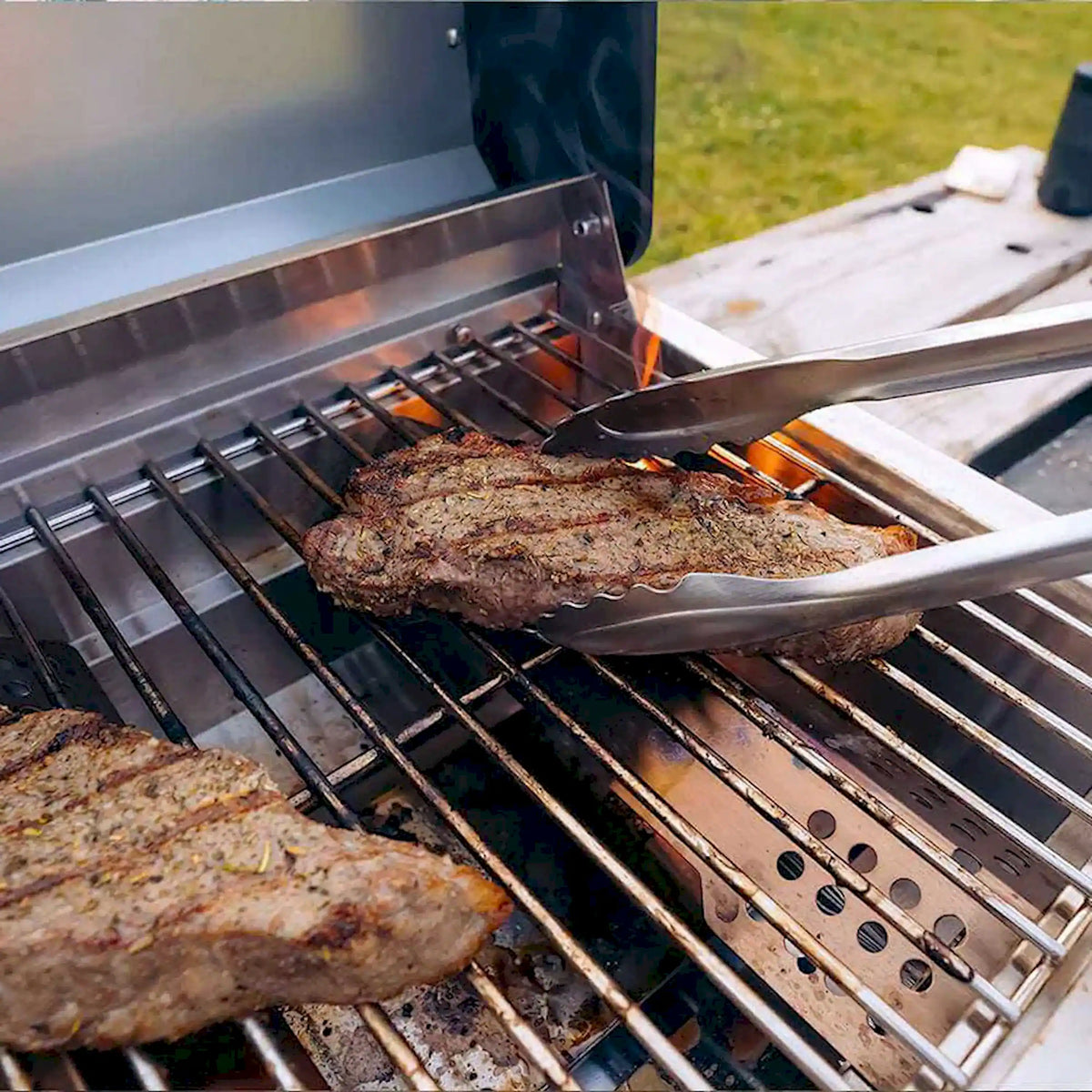 Tabletop propane grill interior with burgers on metal grates