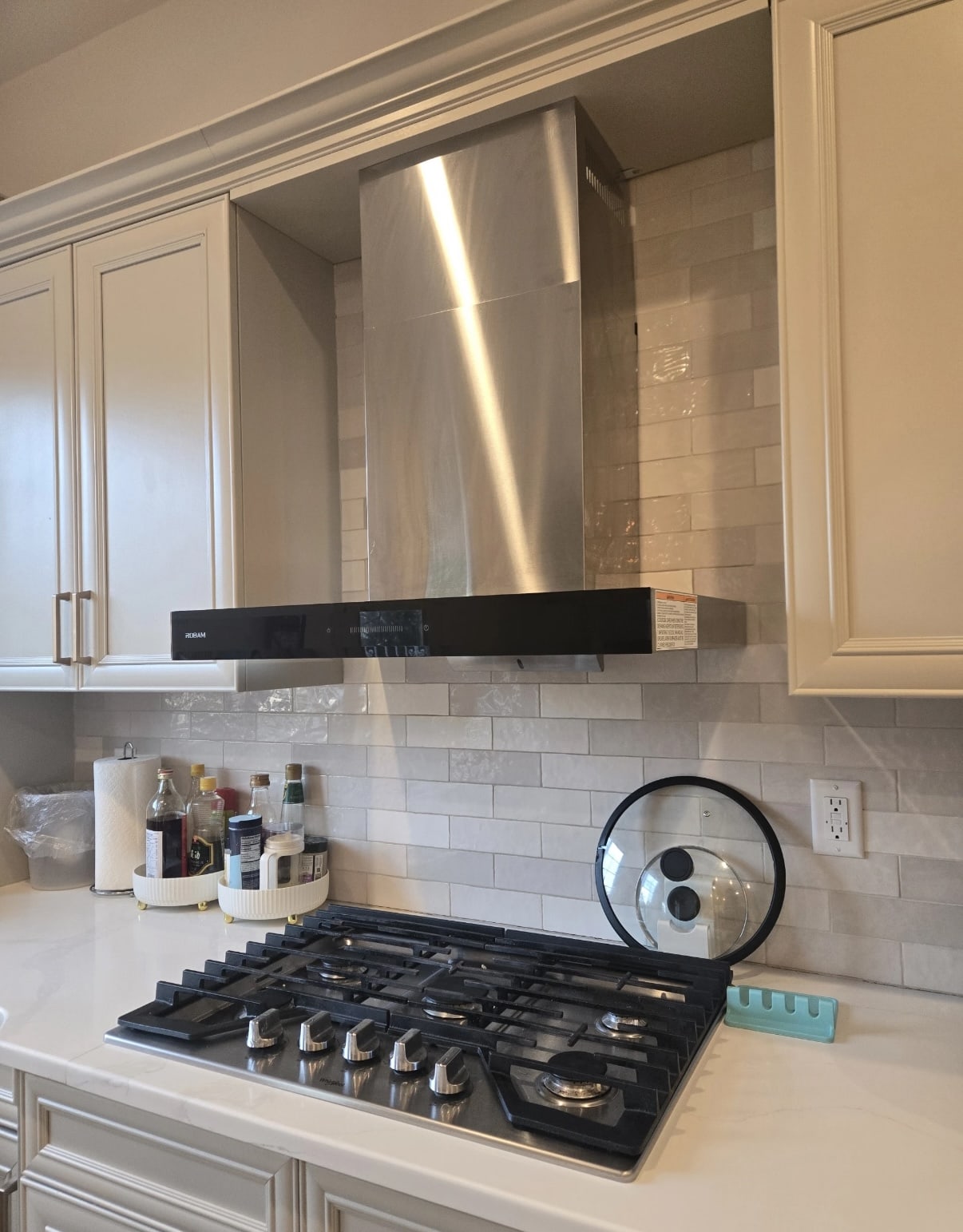 Range hood chimney cover in stainless steel, installed above stove