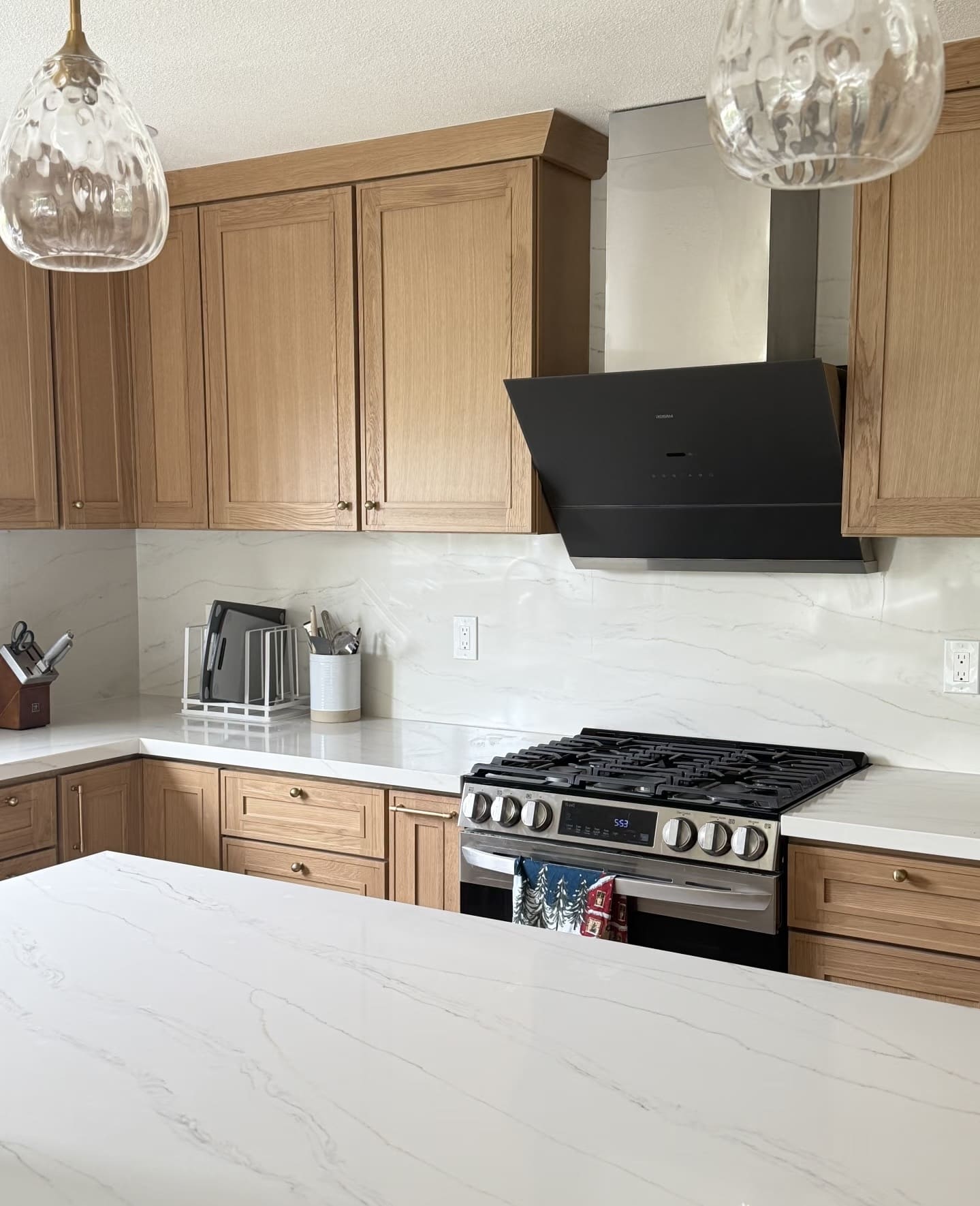 Black range hood chimney cover housing above cooktop, smooth metal finish.