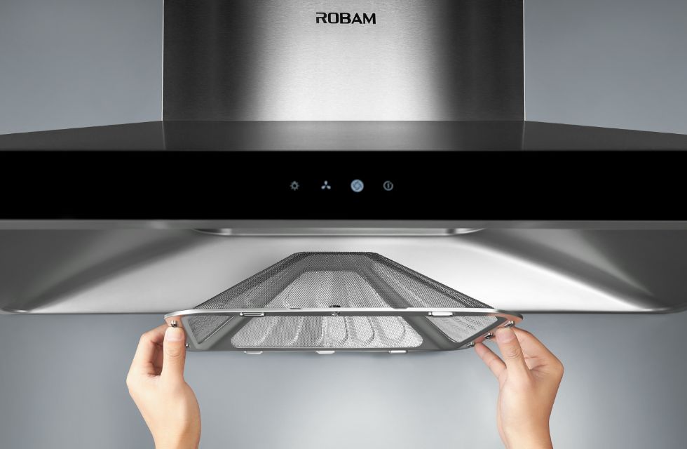 Range hood filter under the hood, hands holding the metal mesh frame