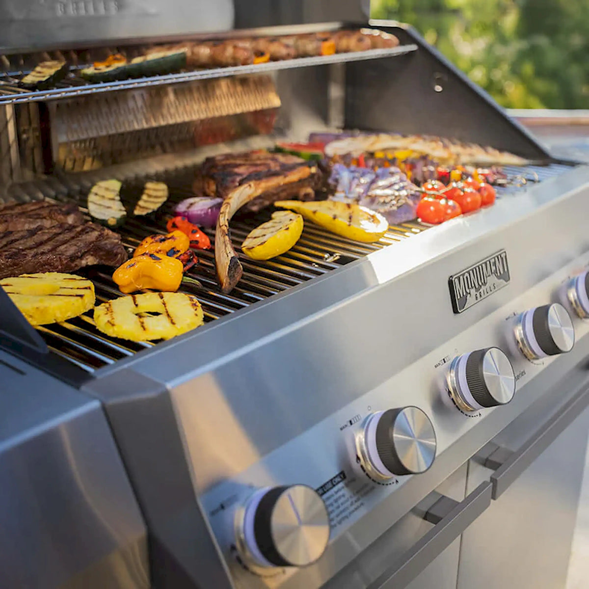 Close-up of food on stainless grill grates under open lid on Monument grill