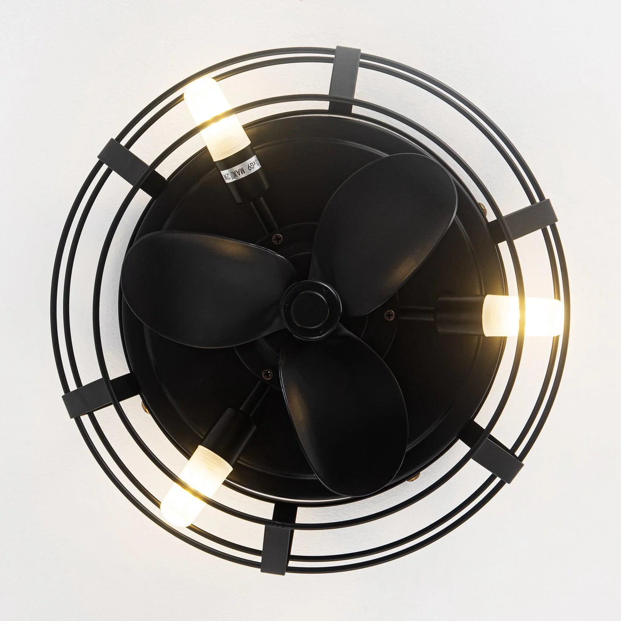 Top view of black caged ceiling fan with integrated light and four fan blades