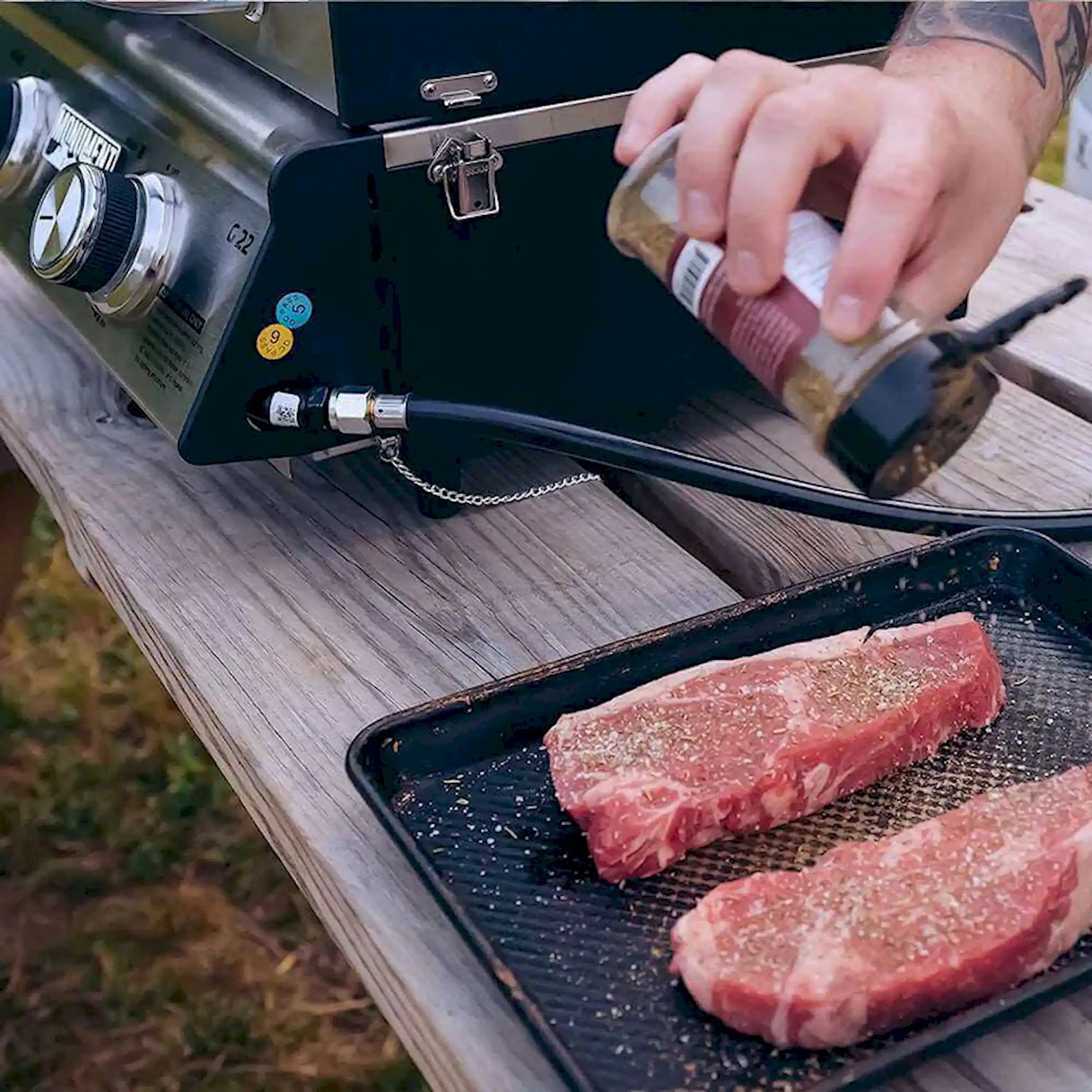 Tabletop propane grill with steaks cooking on the grates