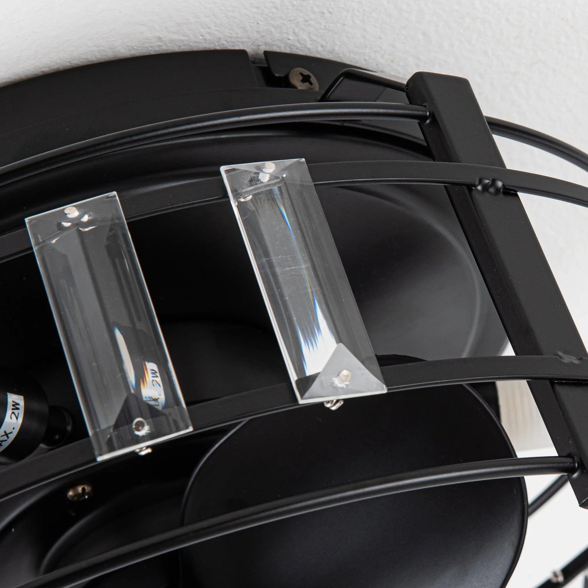 Close-up of black fan housing with crystal glass light shades and metal frame