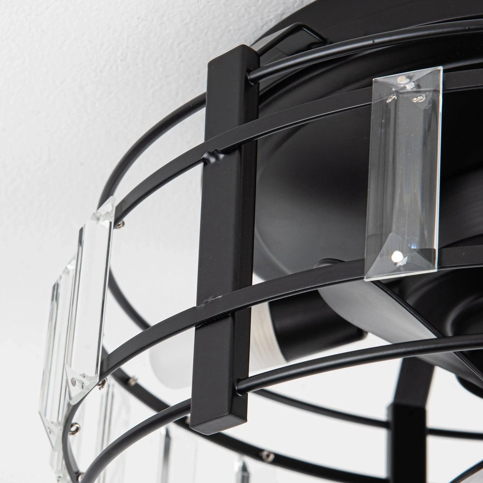 Close-up of black ceiling fan light cage with clear crystal glass panels