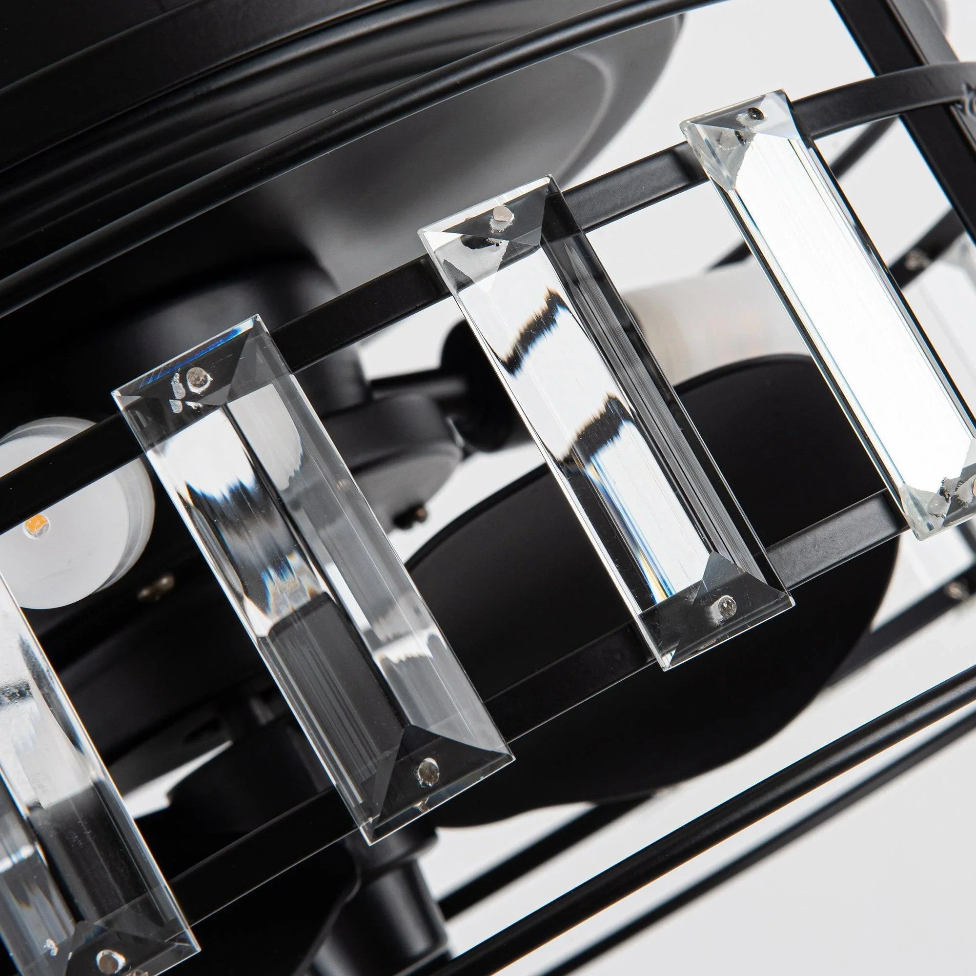Close-up of clear crystal glass light shades on black metal fan frame
