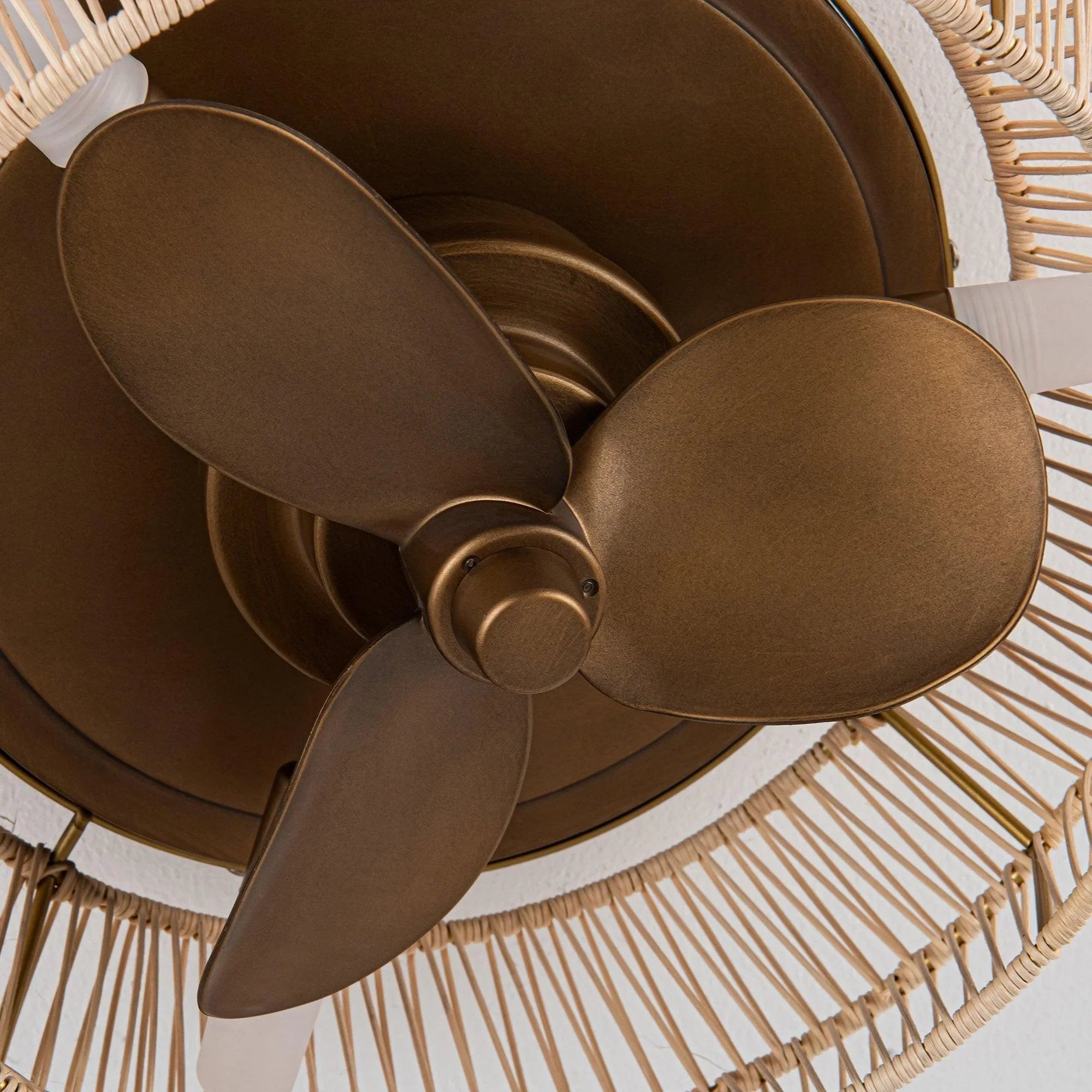 Close-up of golden ceiling fan motor hub with three dark blades