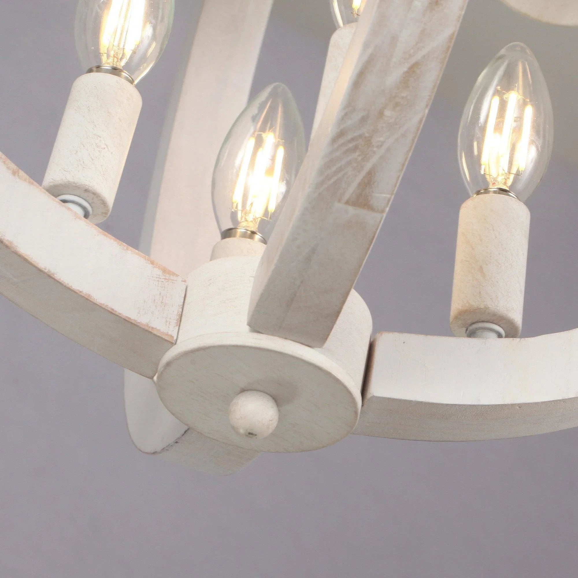 Ceiling fan light sockets with glowing bulbs on white support arms, close-up