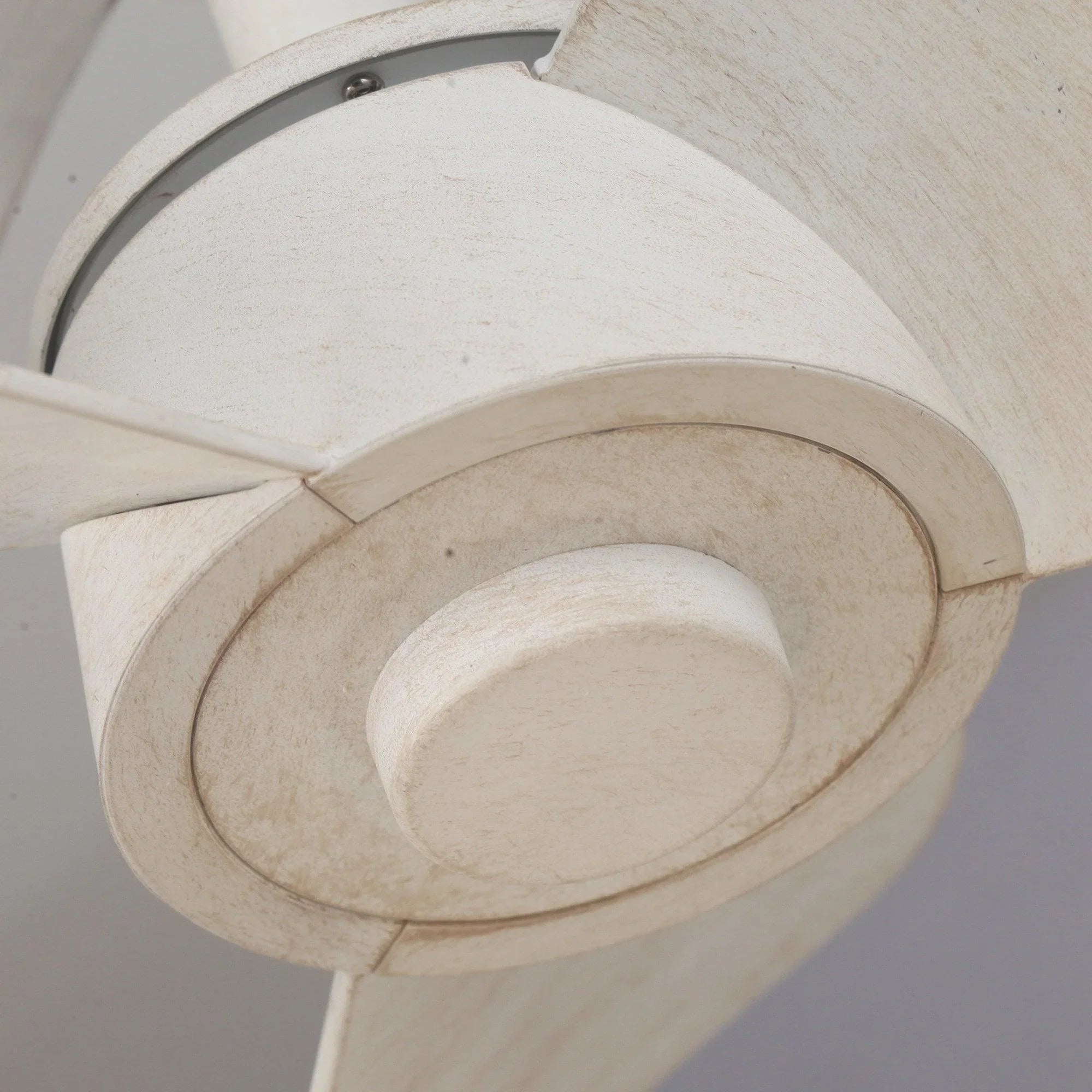 Ceiling fan blade arm and round motor cover in distressed white finish, close-up