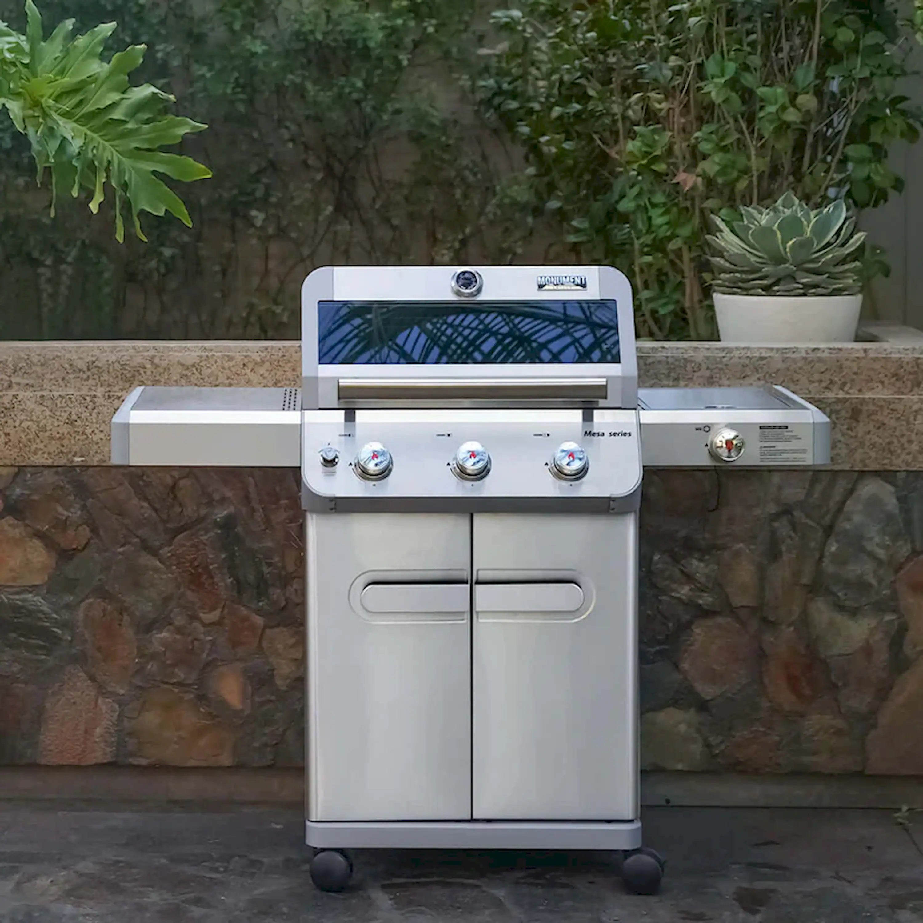 Stainless steel propane grill showing front doors, control knobs, and wheels
