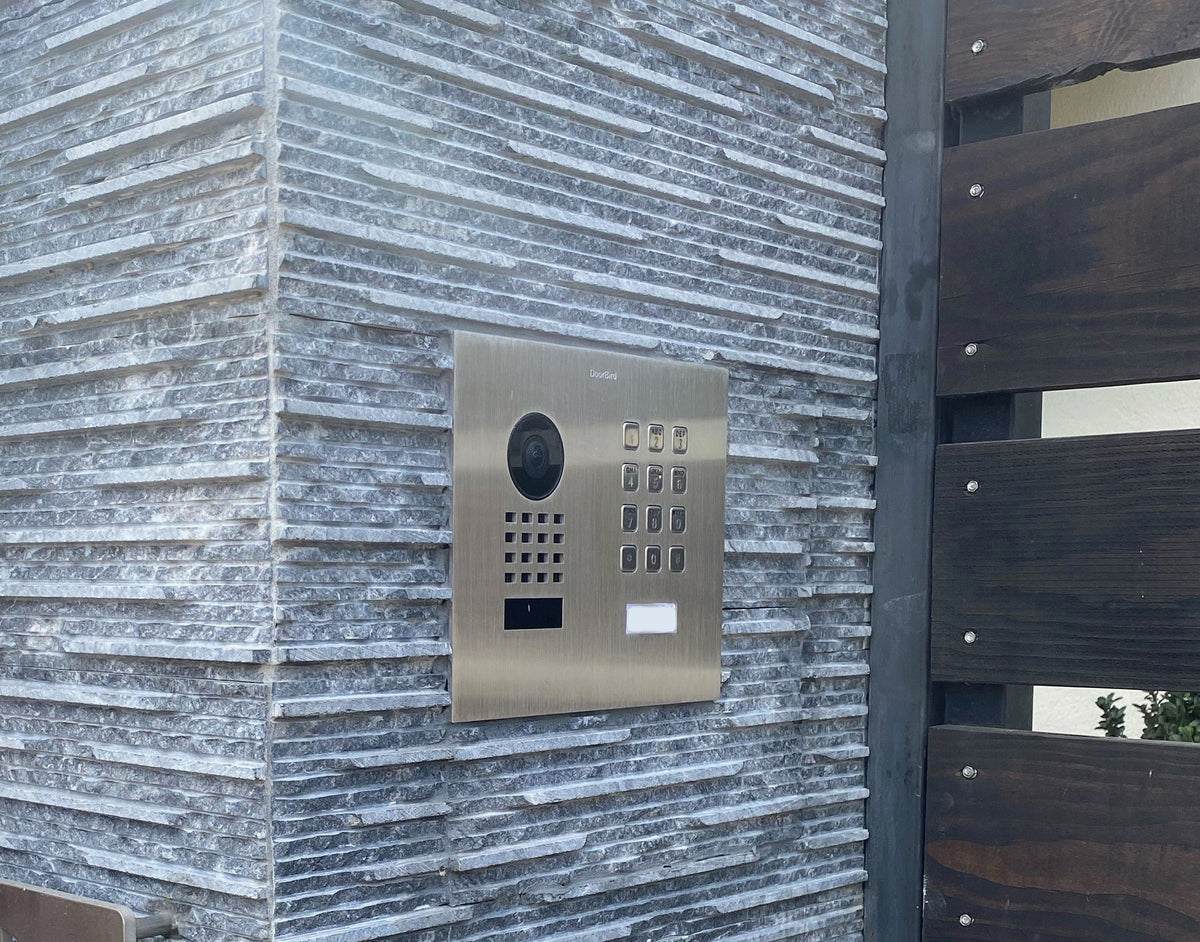 DoorBird outdoor flush-mount IP video door station on wall with camera and keypad