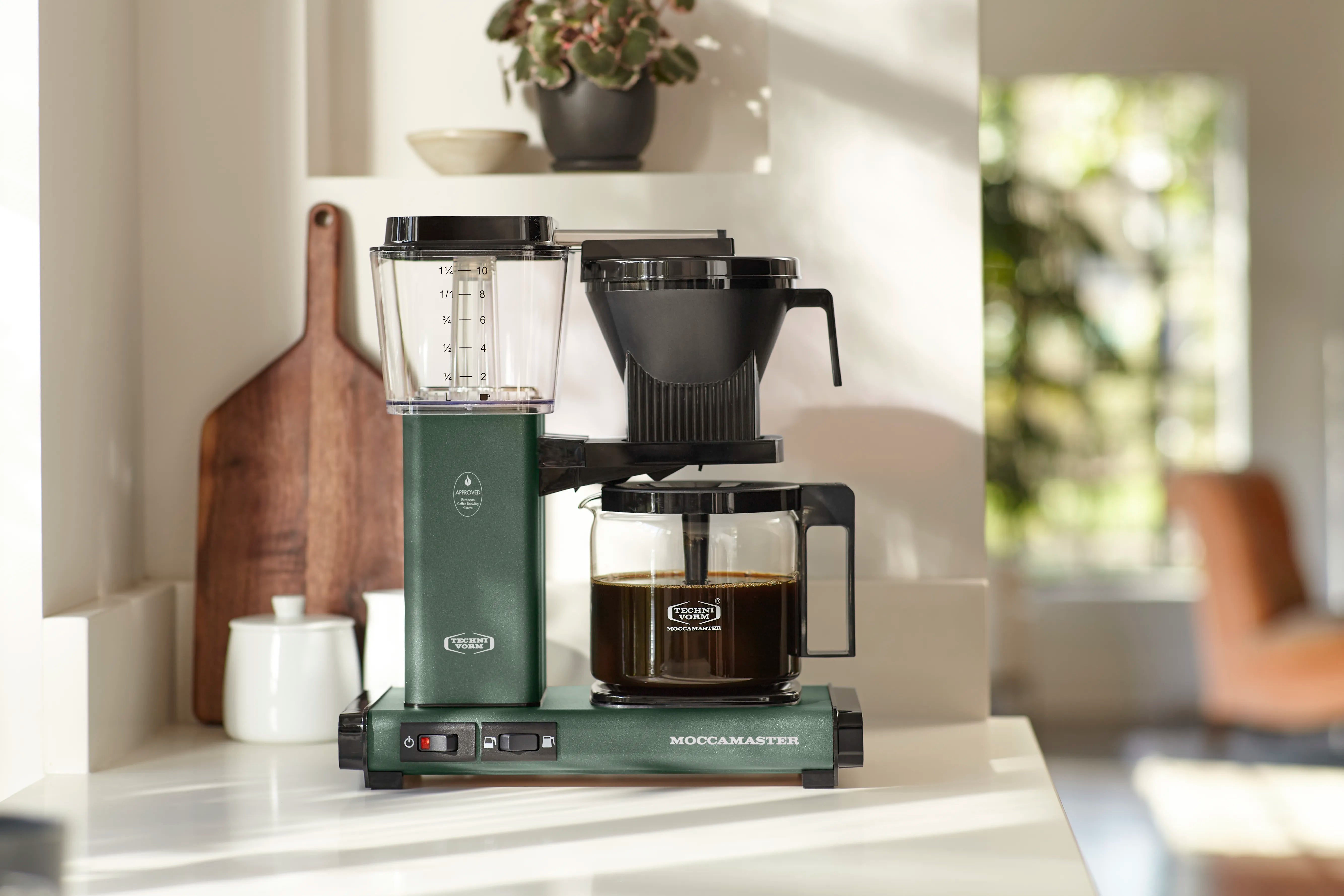 Juniper green coffee maker with glass carafe and black filter basket, drip-ready setup