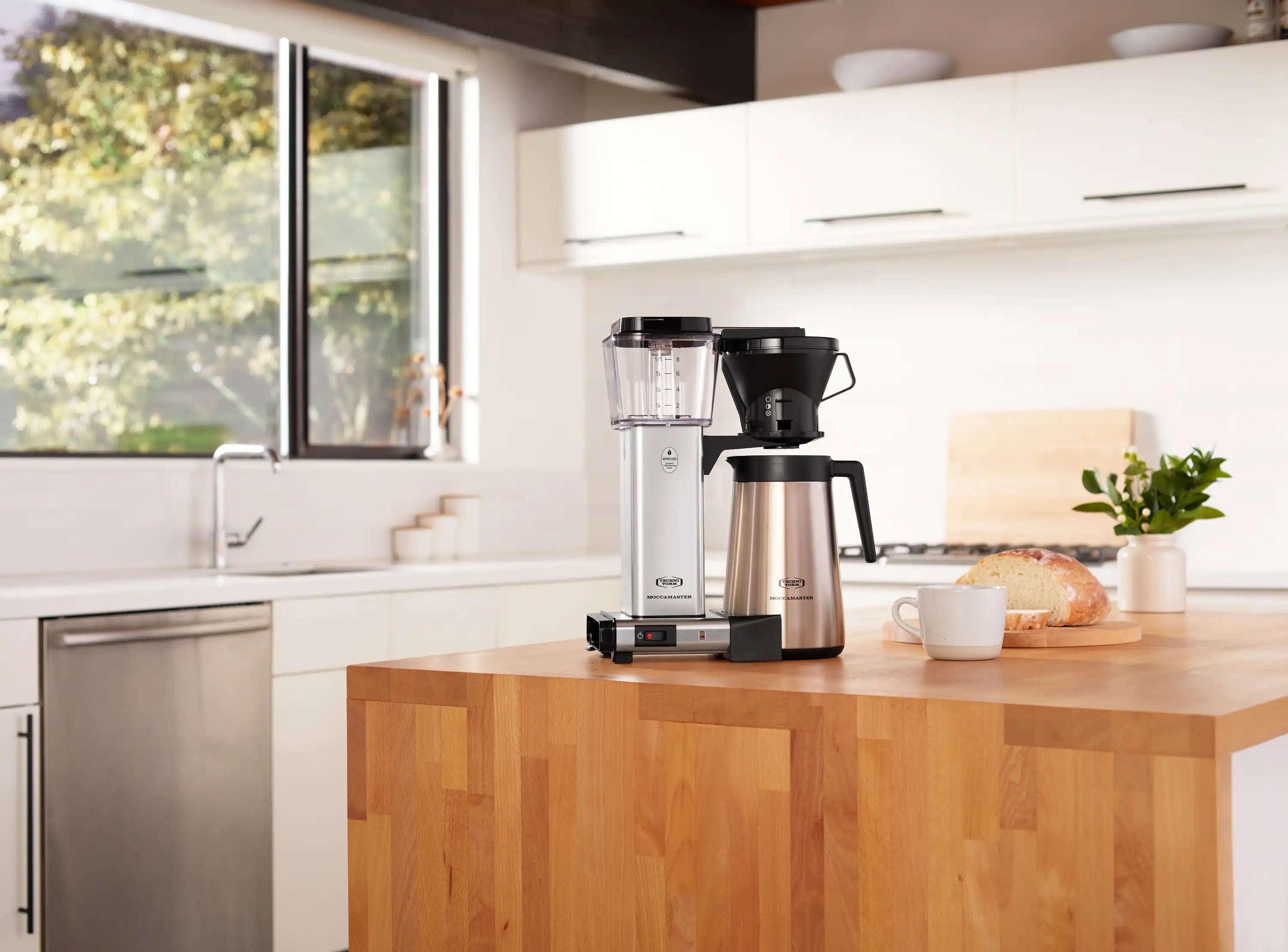 Silver thermal carafe coffee maker with clear water tank, black hopper, and carafe