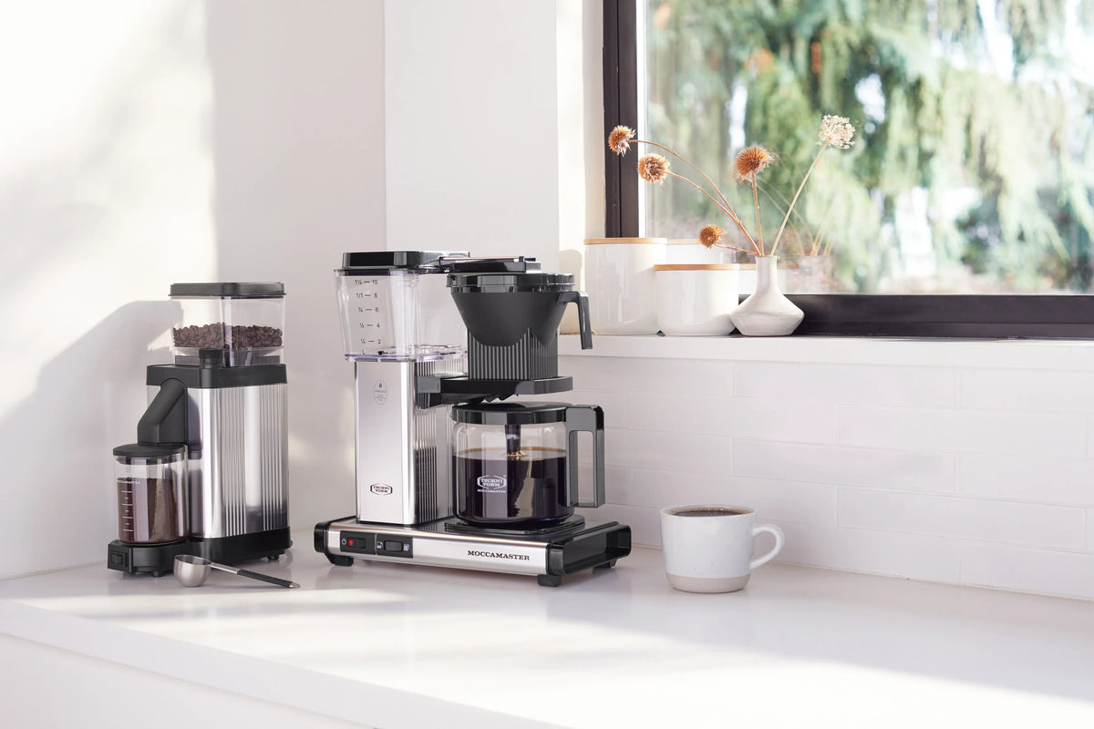 Polished silver burr grinder with clear bean hopper and black grinding chute
