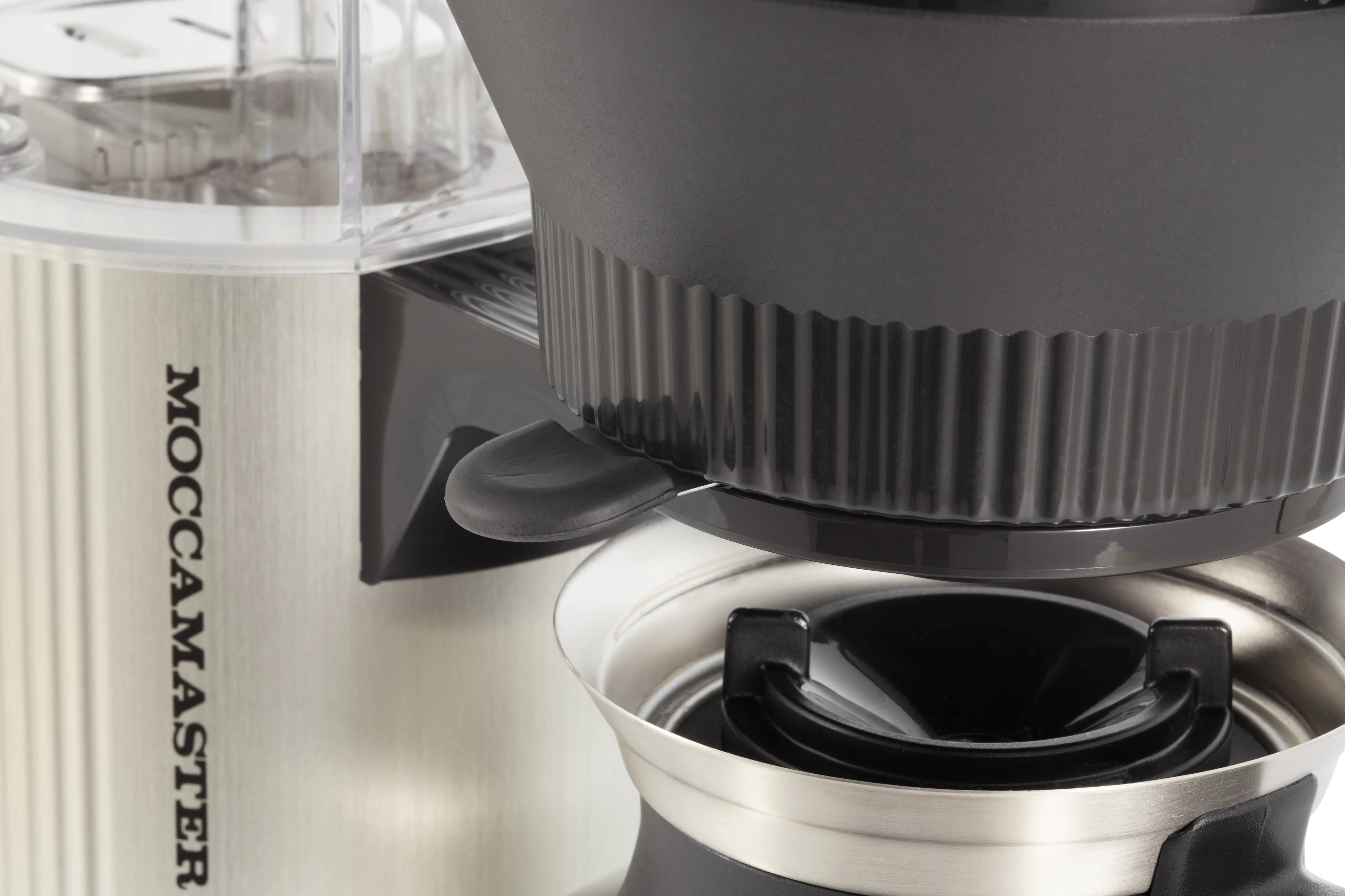 Brushed silver coffee maker brew head and black filter holder, close-up detail