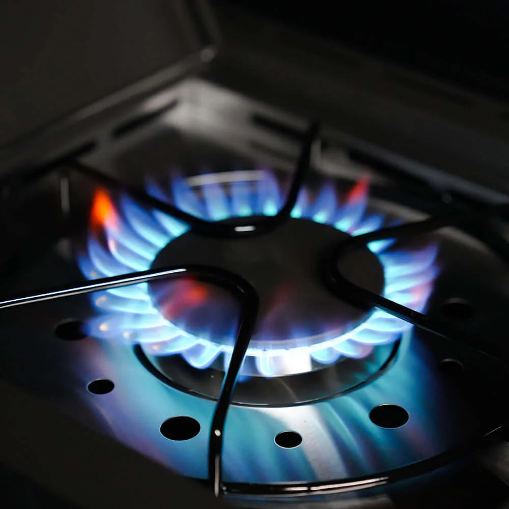 Burning propane flames in a gas grill burner area under the cooktop