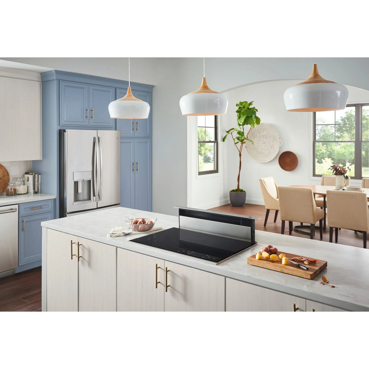 Downdraft range hood over black cooktop in a white kitchen with cabinets