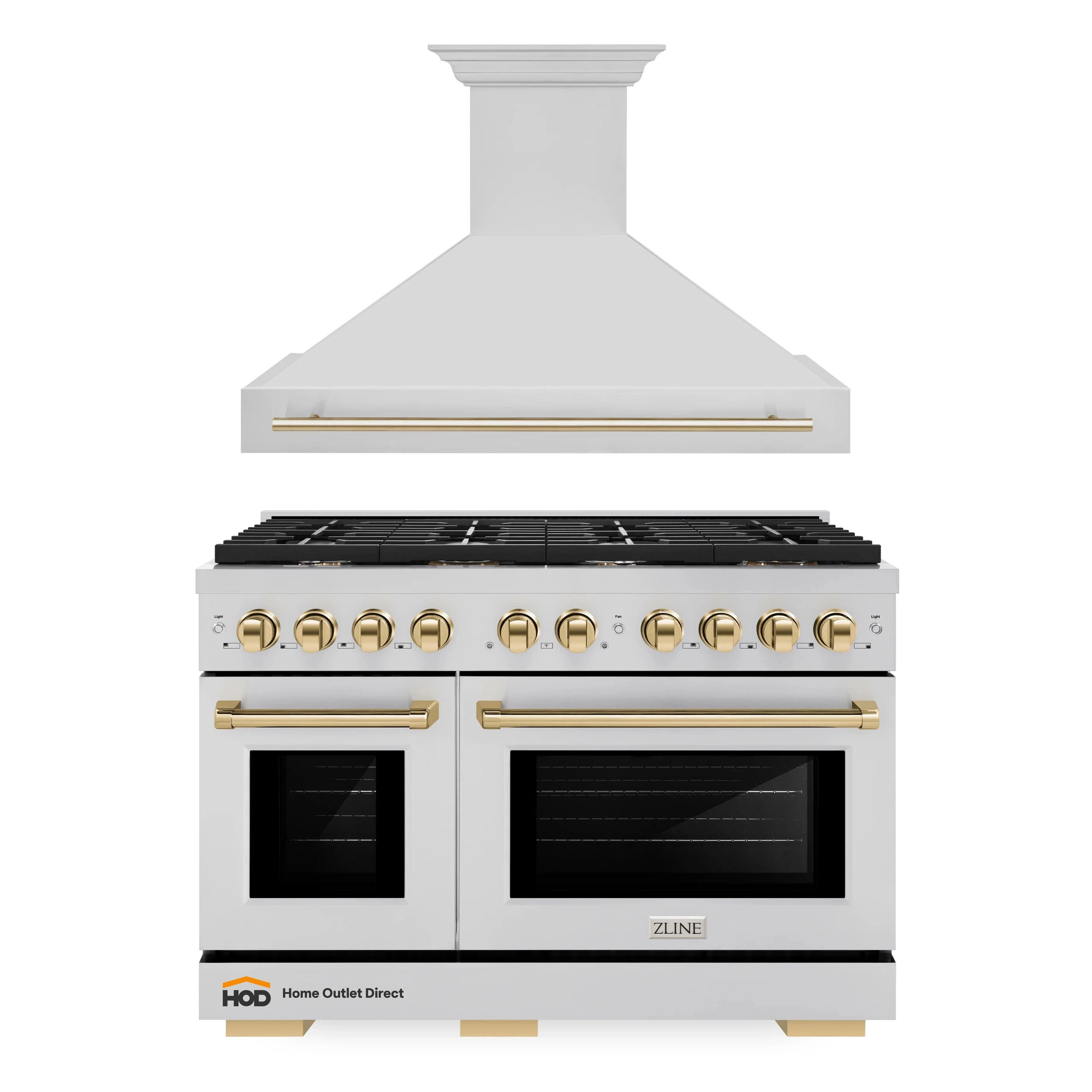 Stainless steel gas range with wall-mounted range hood, gold trim, and black cooktop