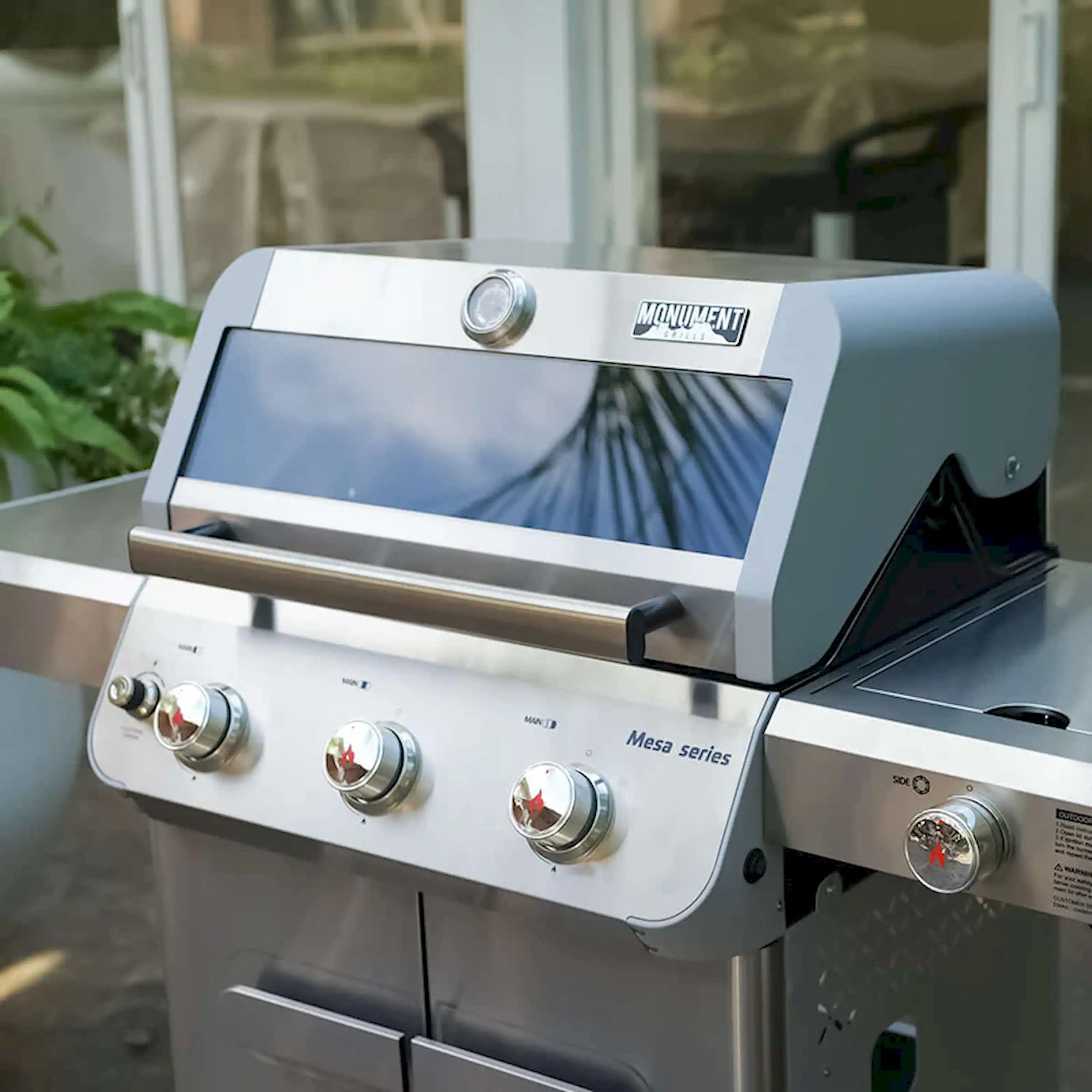 Front view of stainless steel propane grill with control knobs and open hood