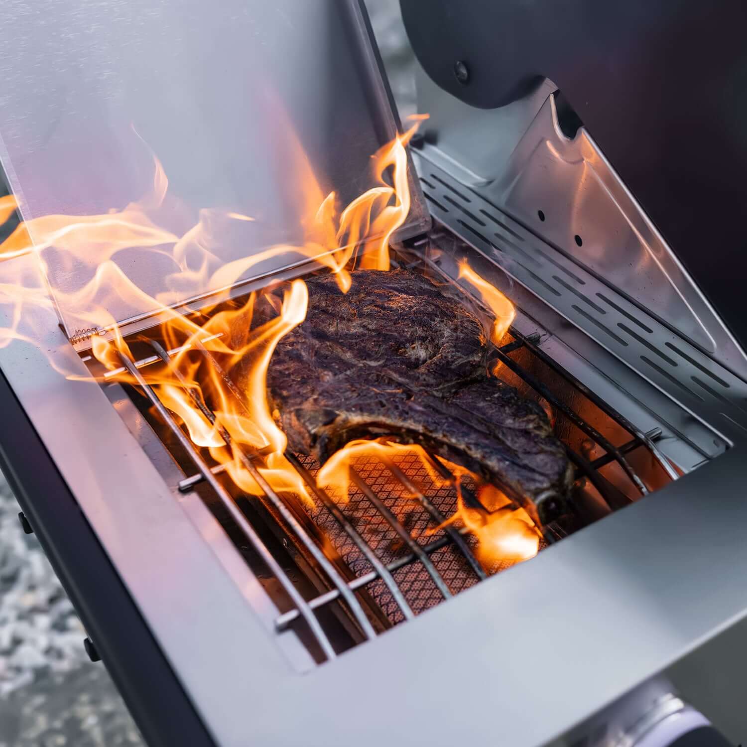 Propane gas grill with flames and glowing burner heat inside the cooking chamber