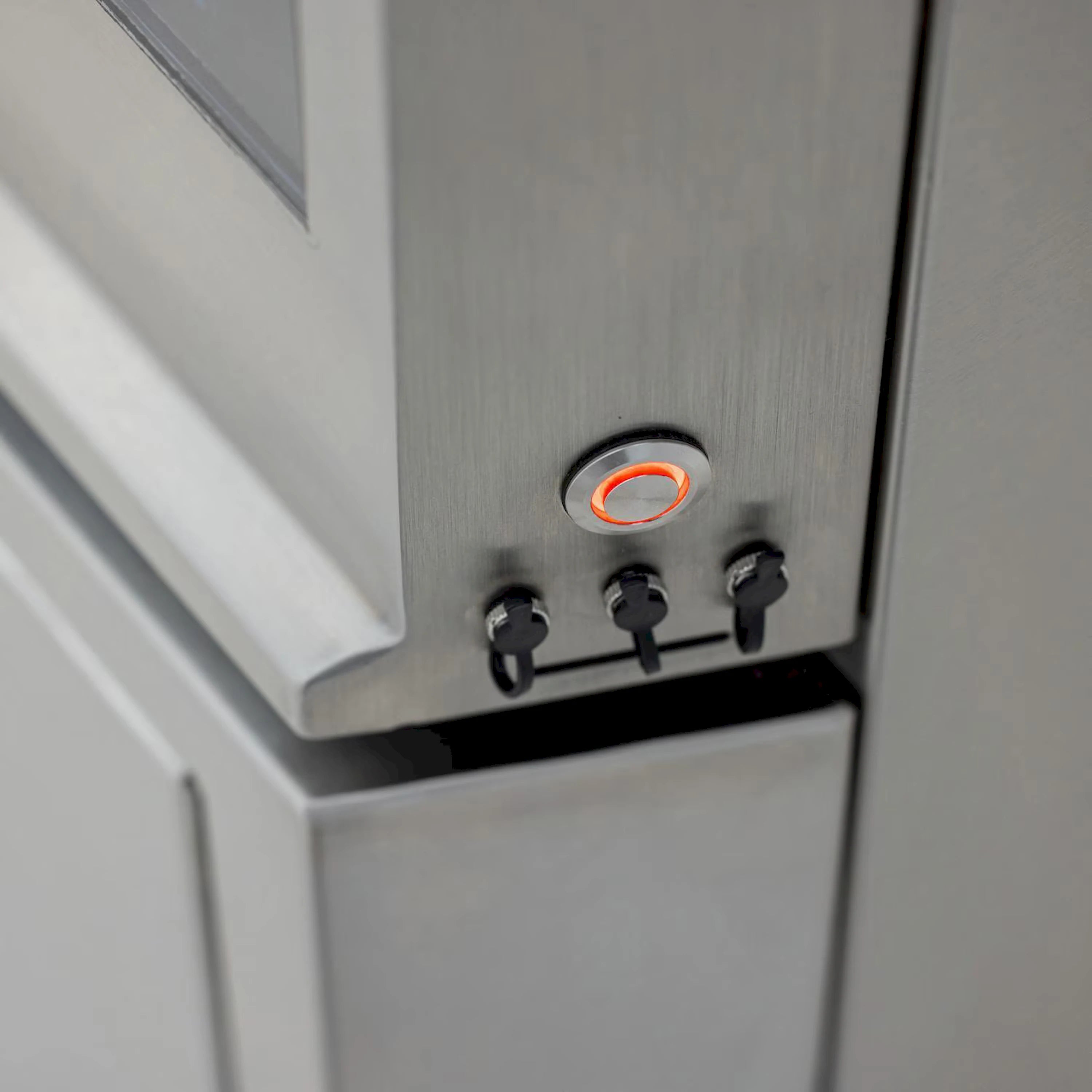 Stainless steel control panel with three knobs and orange-ring indicator