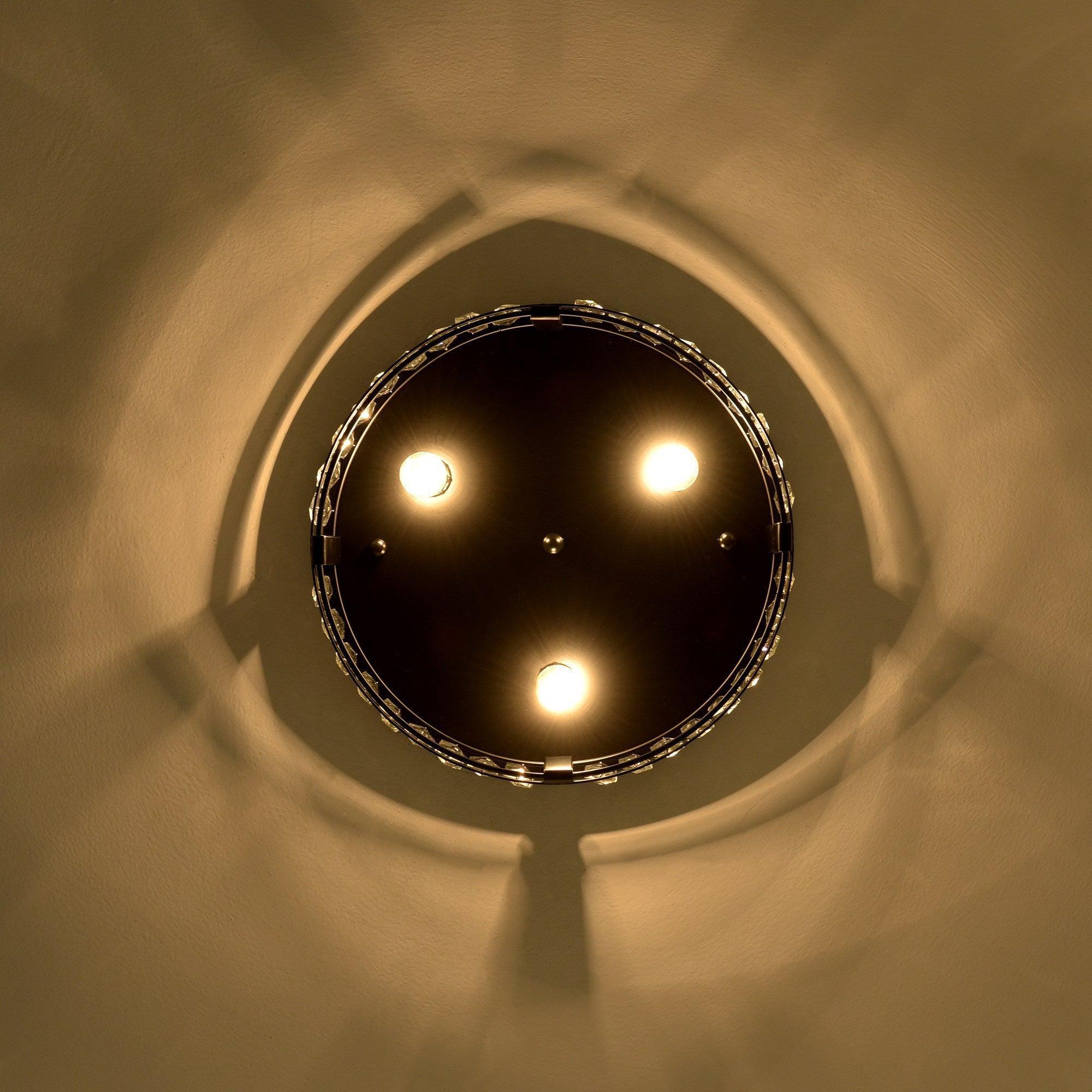 Top view of black flush mount ceiling light with crystal ring and lit bulbs