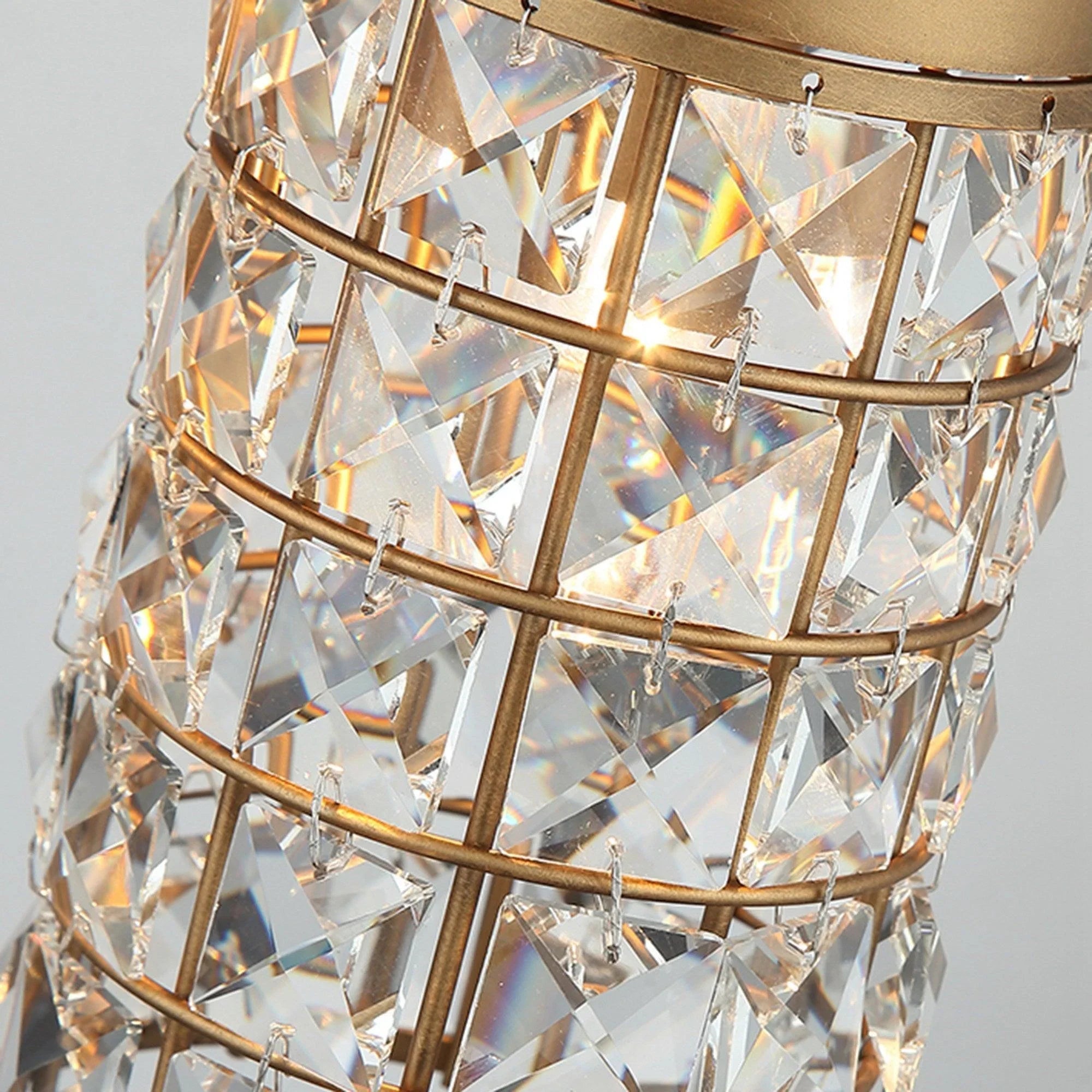 Close-up of golden faceted crystal glass cylinder with metal lattice and lit bulbs