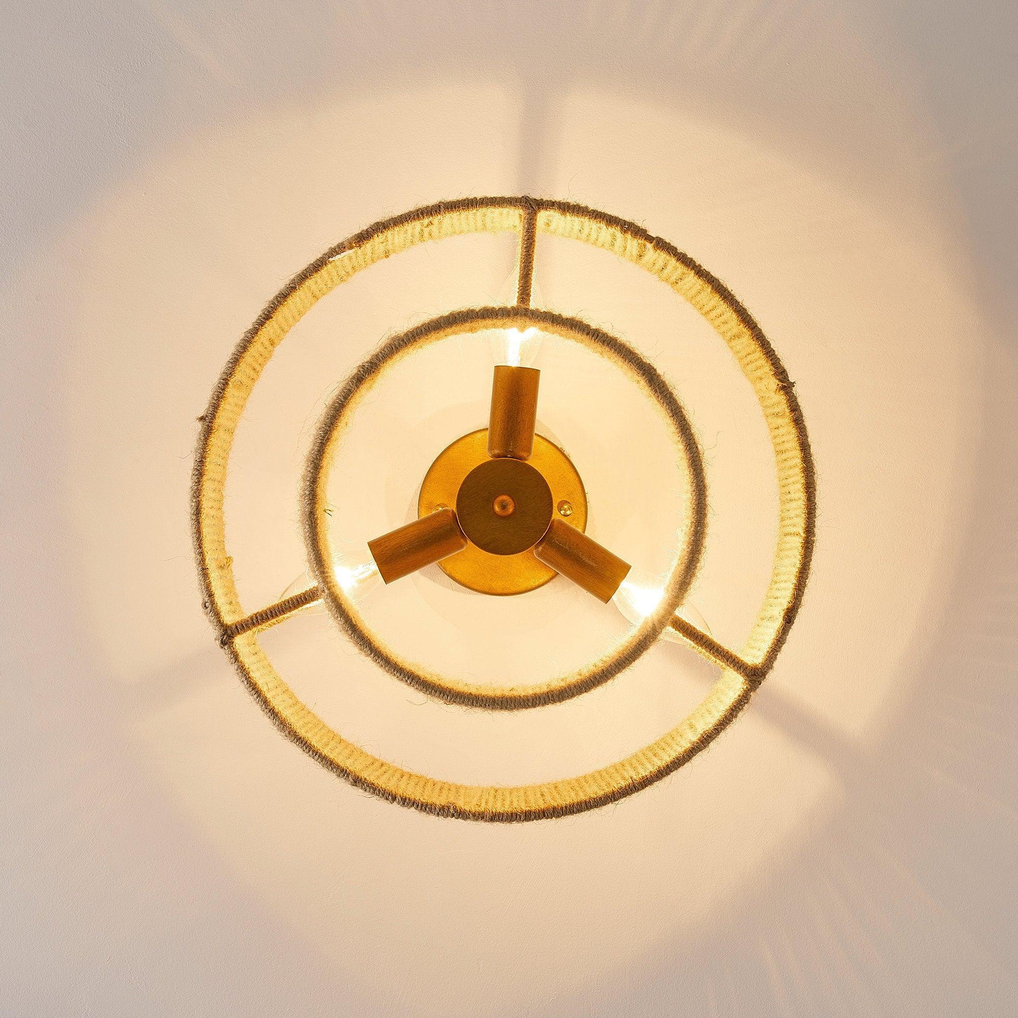 Burning flush mount bulb glow inside golden circular shade frame and arms.