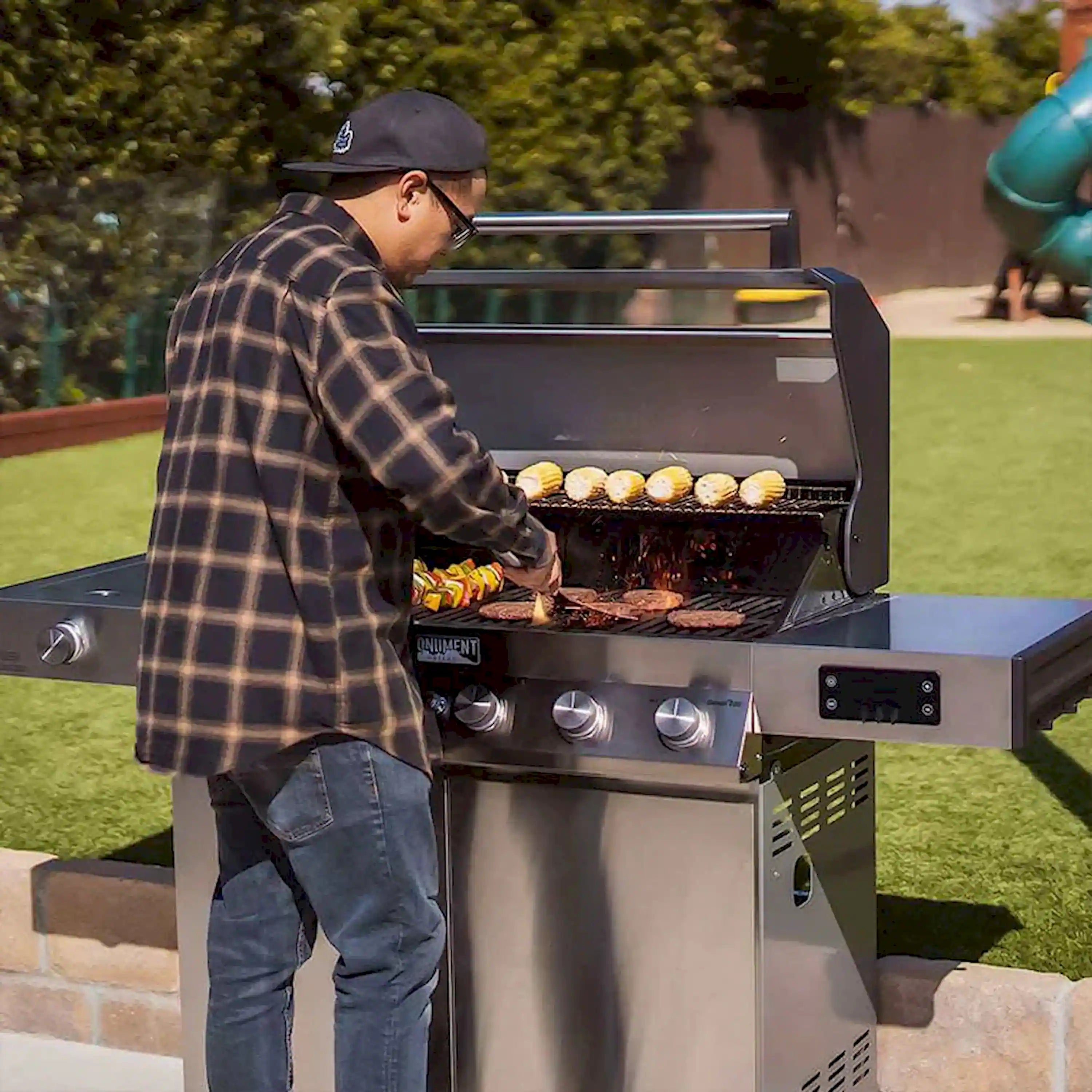 Man grilling food on a stainless steel Monument gas grill with lid open