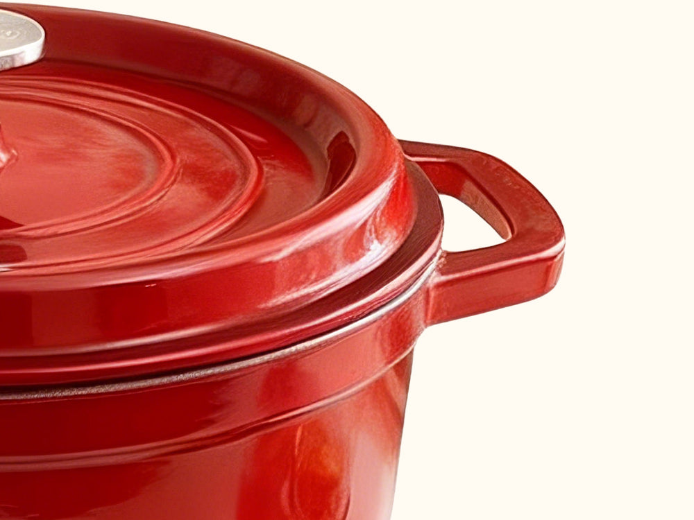 Red enamel Dutch oven with lid, side handle, and curved rim detail