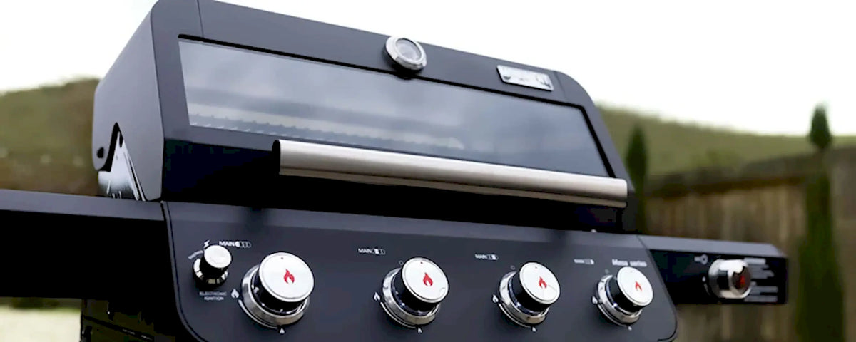 Black 4-burner gas grill front control panel with four temperature knobs