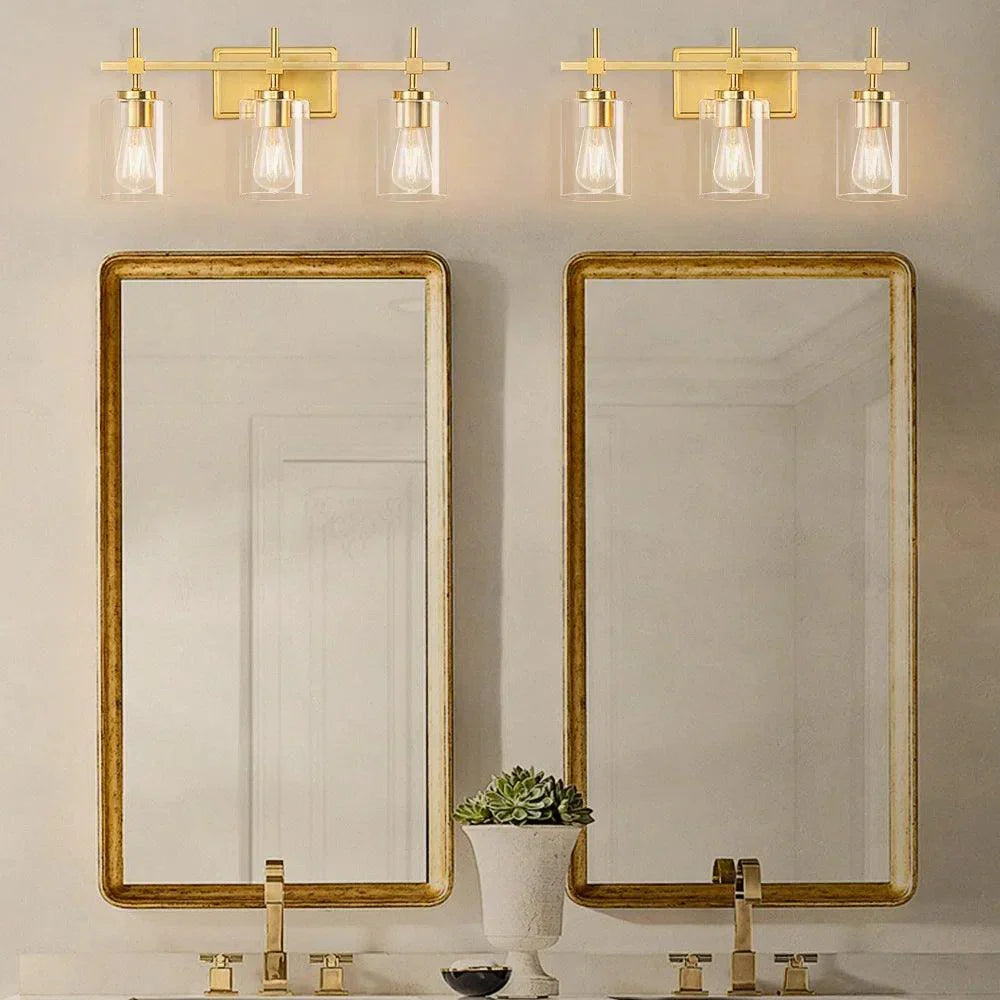 Golden 3-light bathroom vanity light with clear glass shades and metal backplate