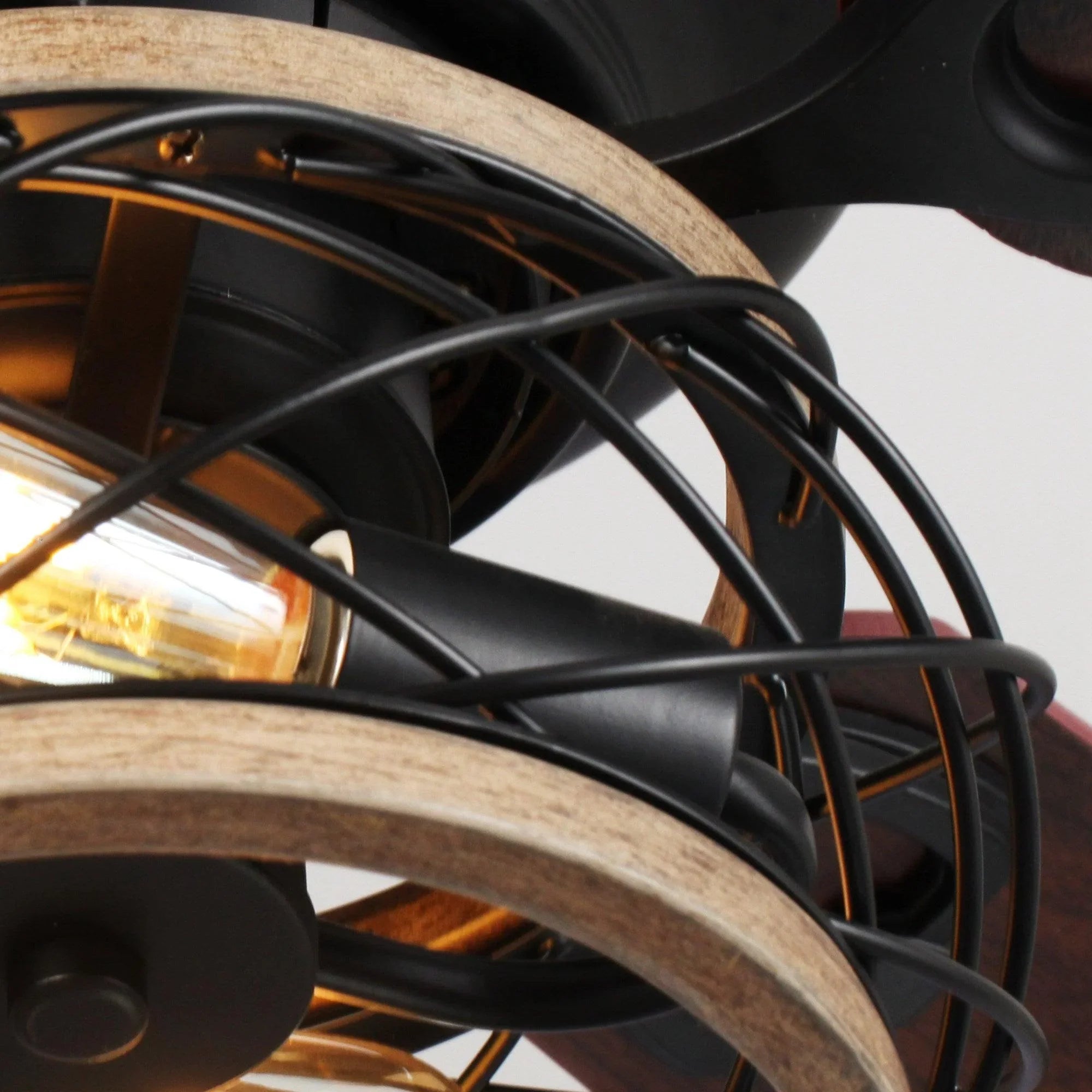 Close-up of black light cage and amber bulb on a farmhouse flush-mount ceiling fan