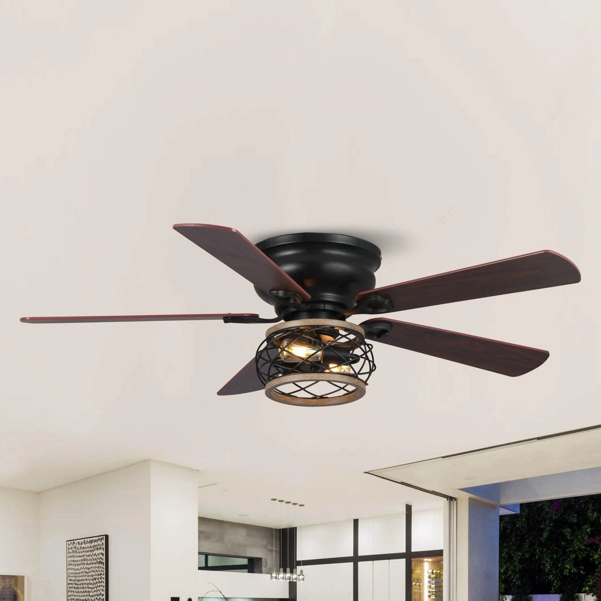 Black flush-mount ceiling fan with wood blades and caged light under the ceiling
