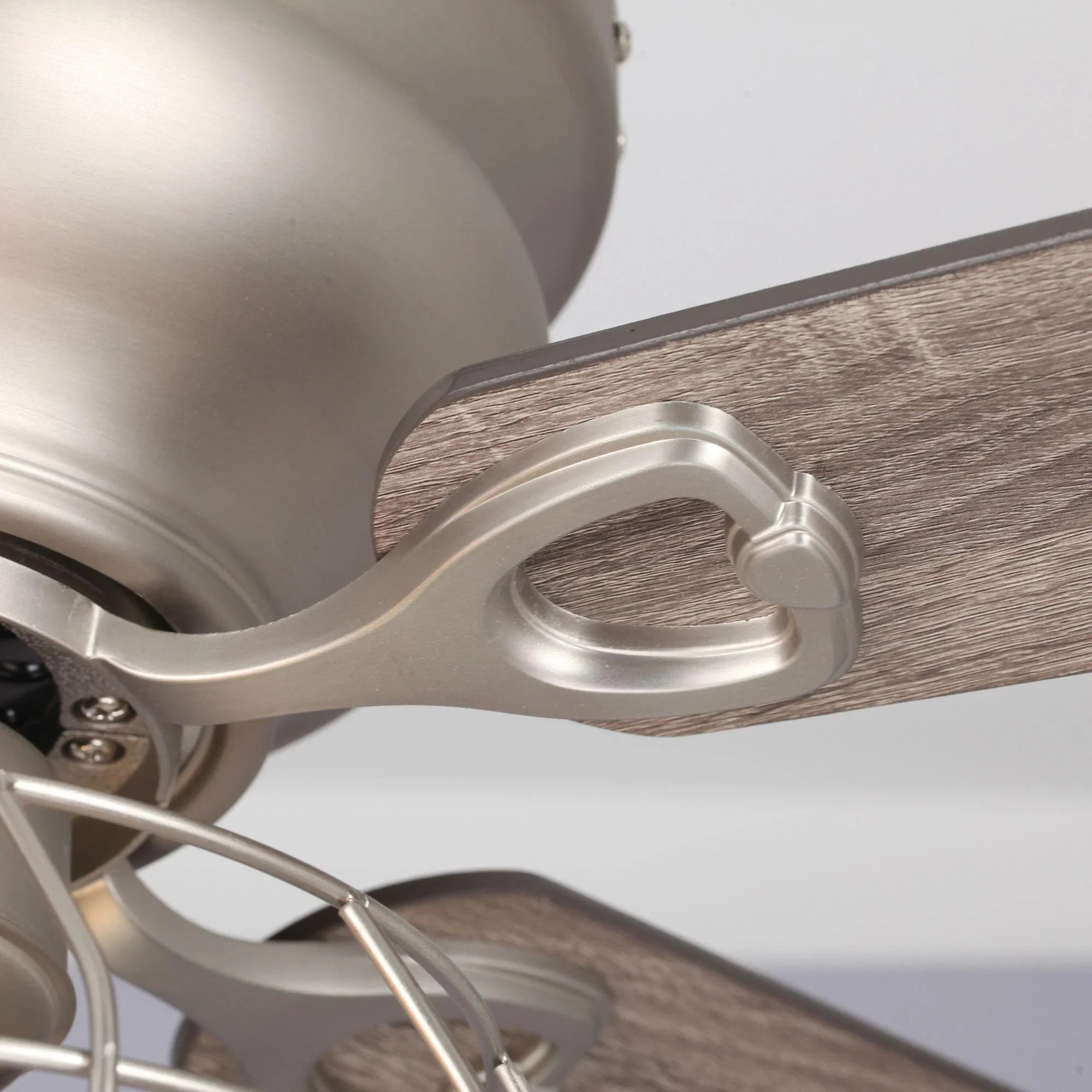 Satin nickel motor housing and blade arm detail on a reversible ceiling fan