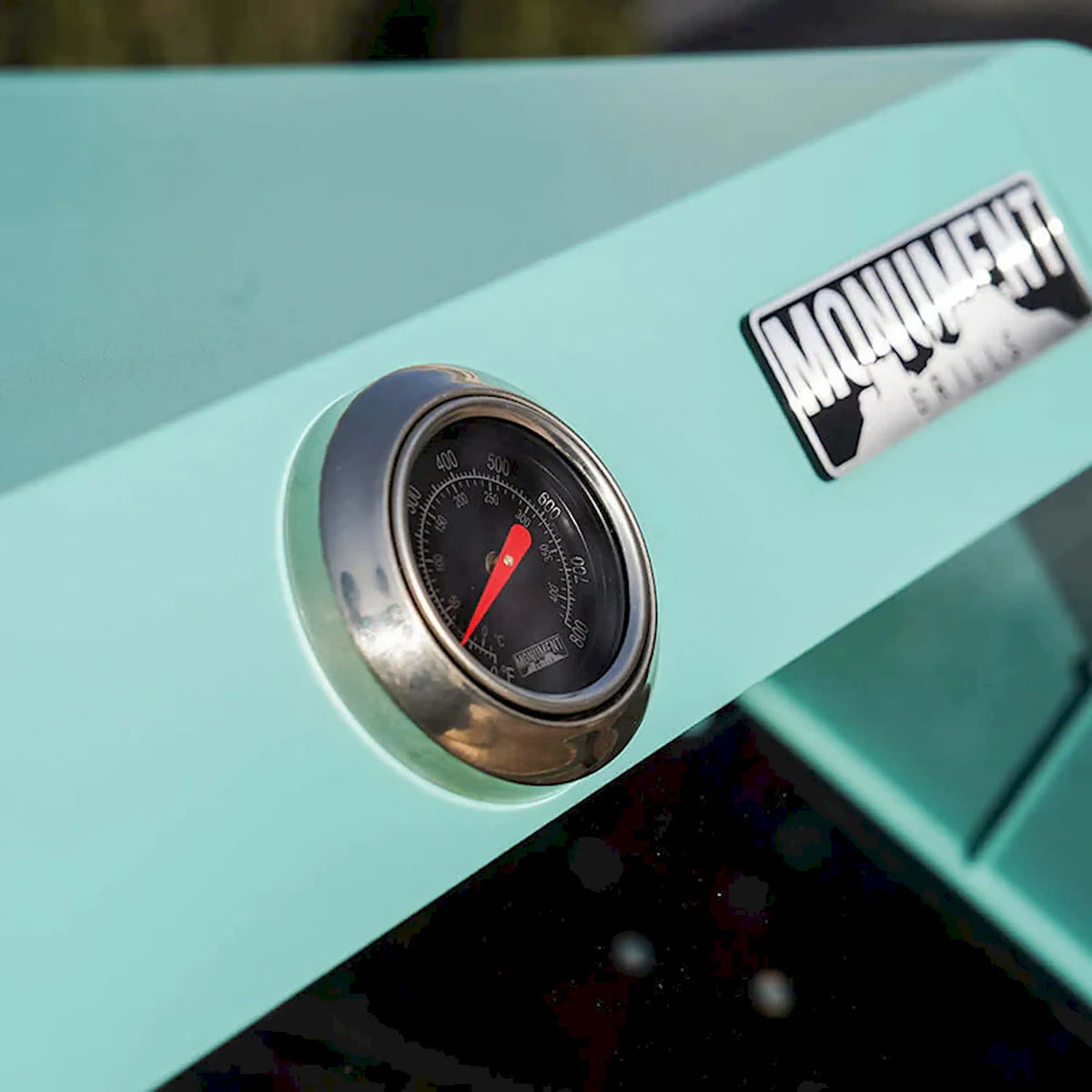 Green propane grill thermometer gauge on control panel, round chrome bezel