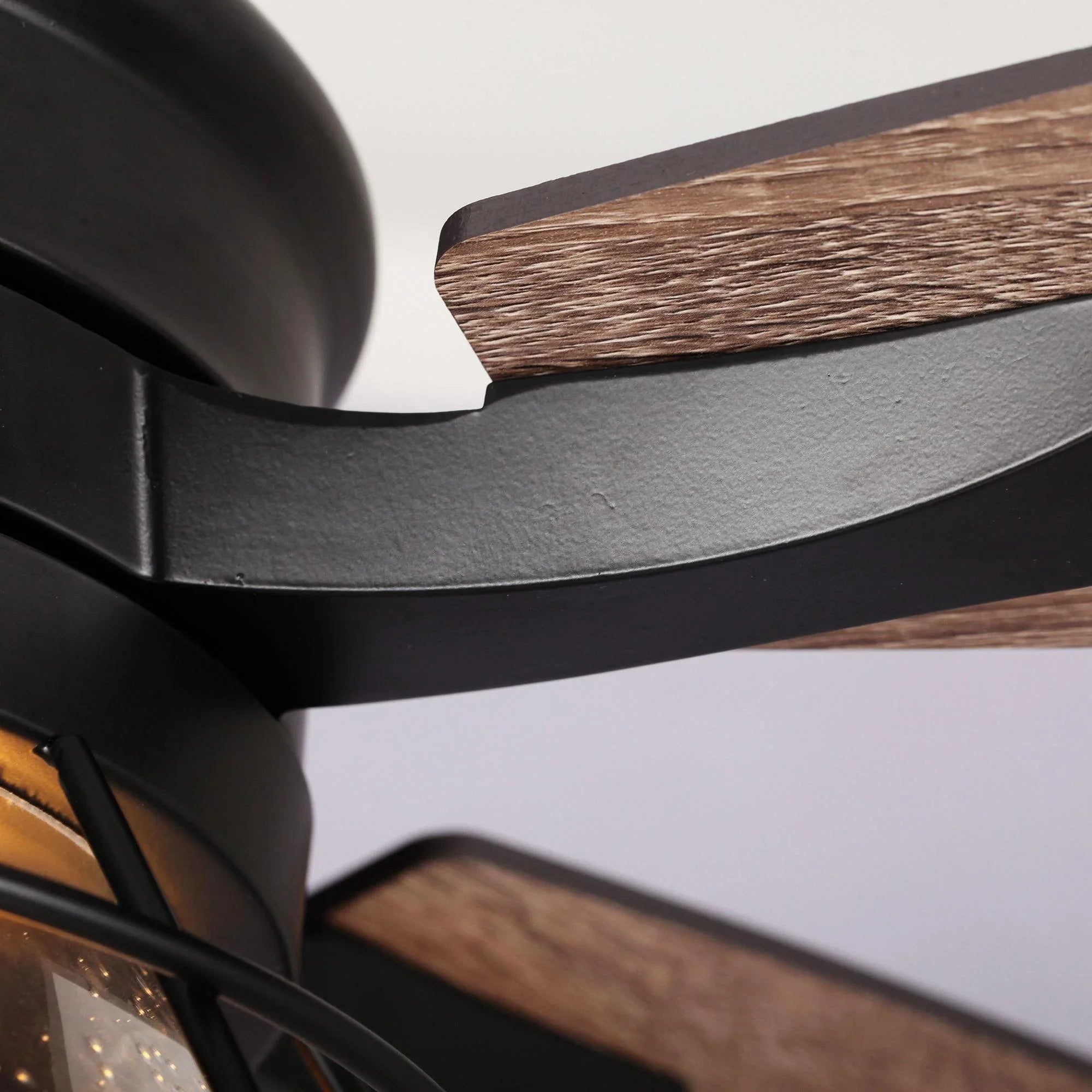 Close-up of black ceiling fan arm and wood blade