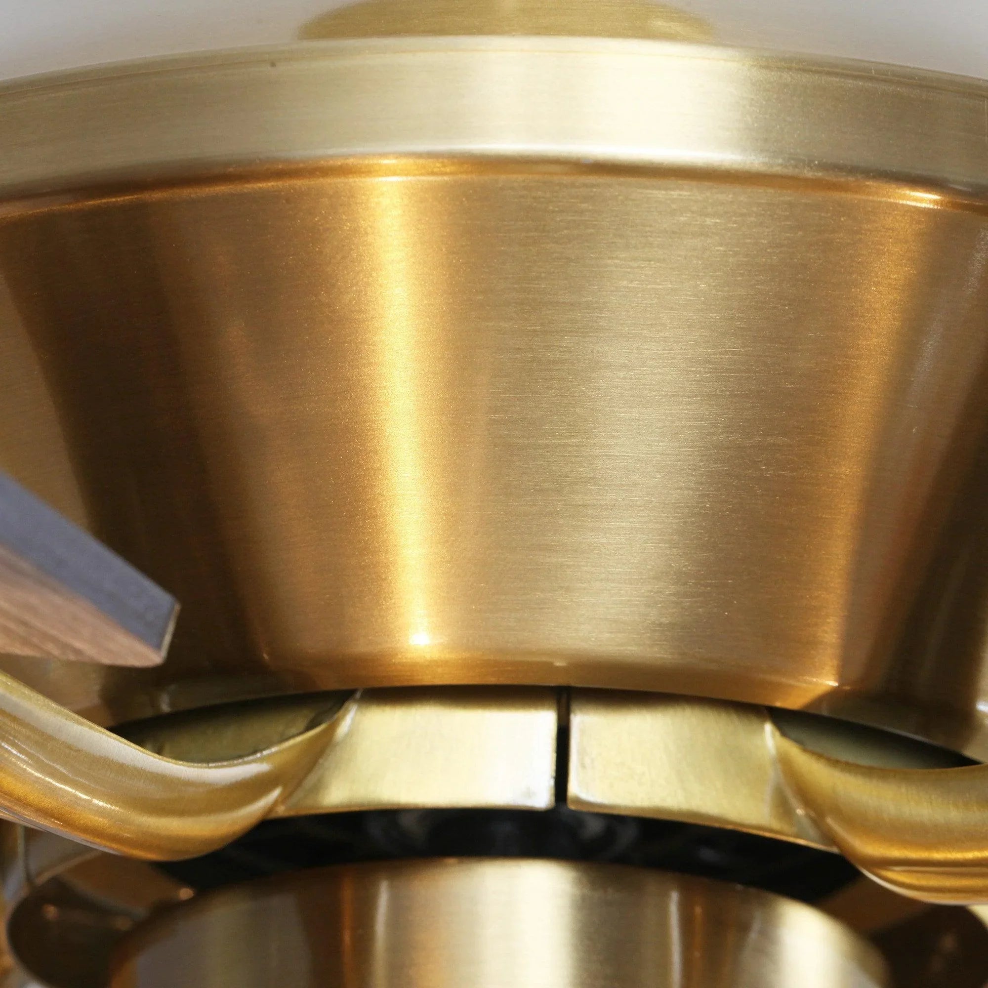 Golden ceiling fan motor housing with decorative blade arms, close-up