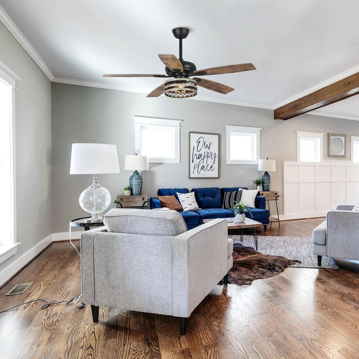 Black ceiling fan with reversible wood blades and decorative caged light in an open living space