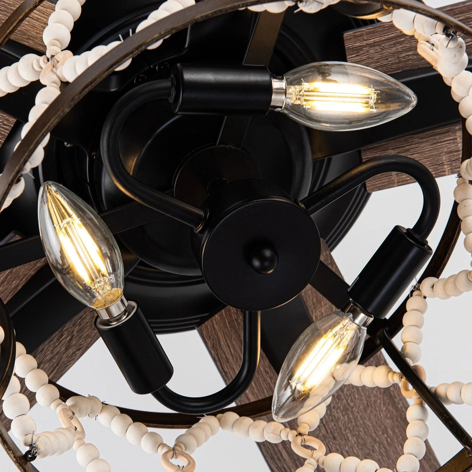 Black ceiling fan with three lit glass shades and wood-toned reversible blades