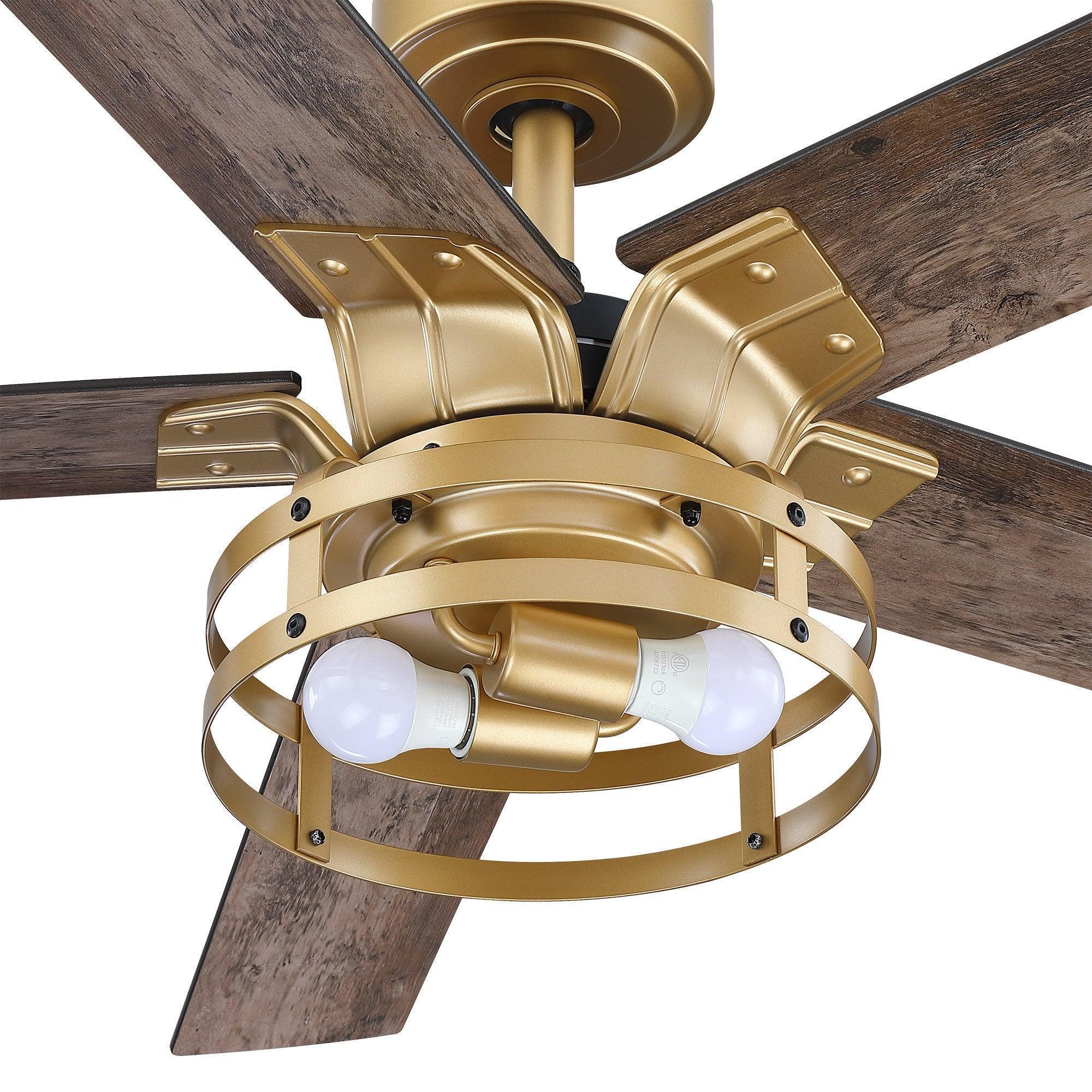 Close-up industrial ceiling fan with light kit, gold housing, and dark wood reversible blades.