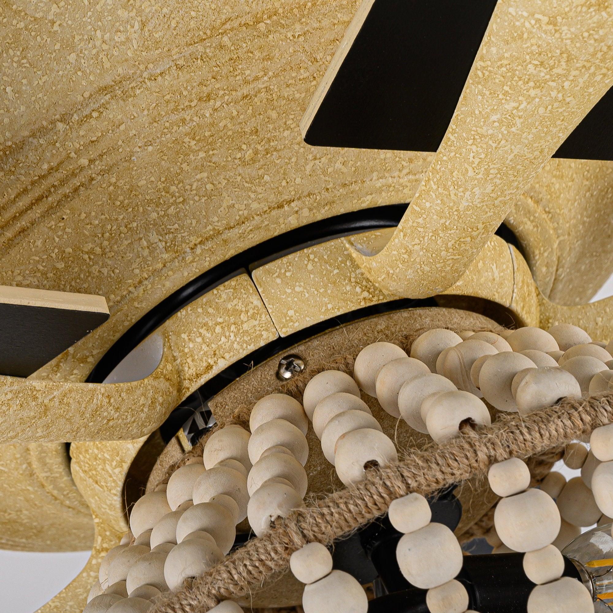 Ceiling fan light detail with gold textured housing and bead-wrapped cover