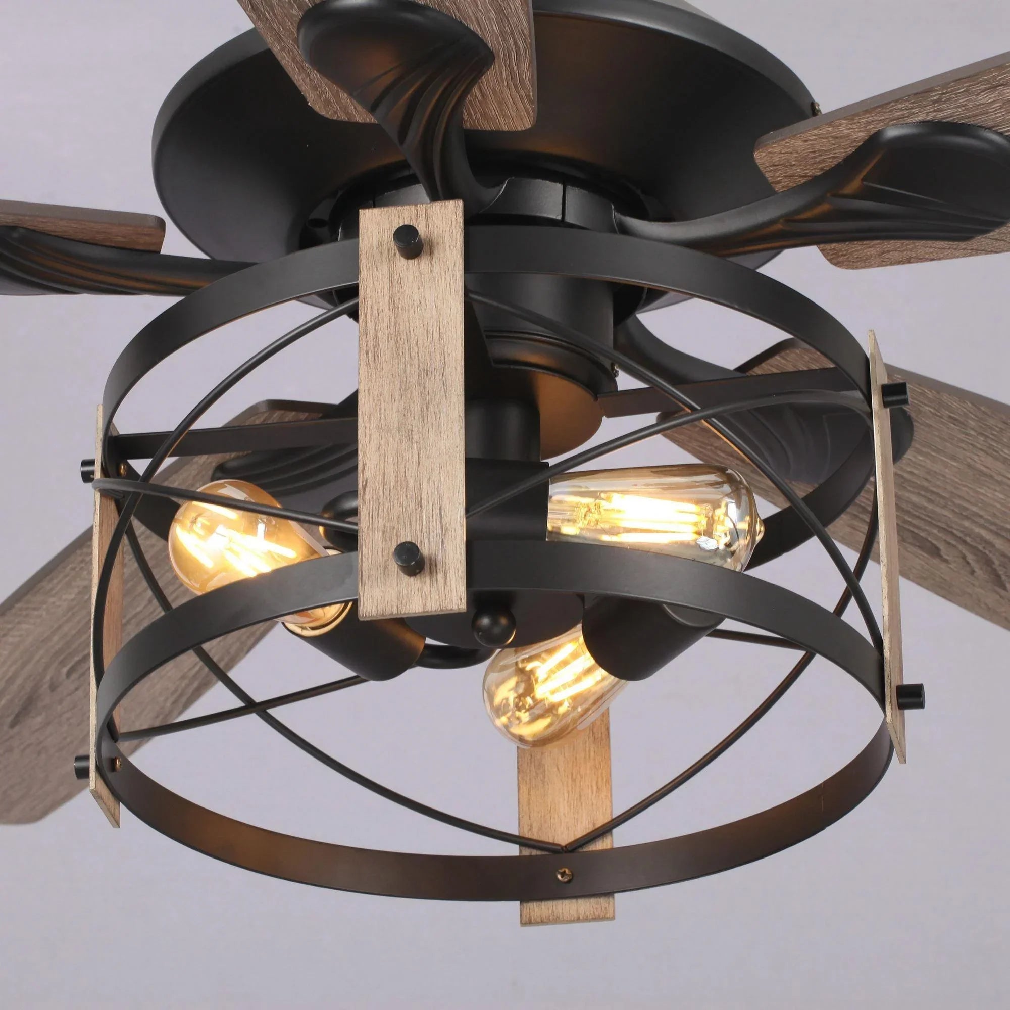 Black ceiling fan light kit with glowing bulbs inside an enclosed metal cage