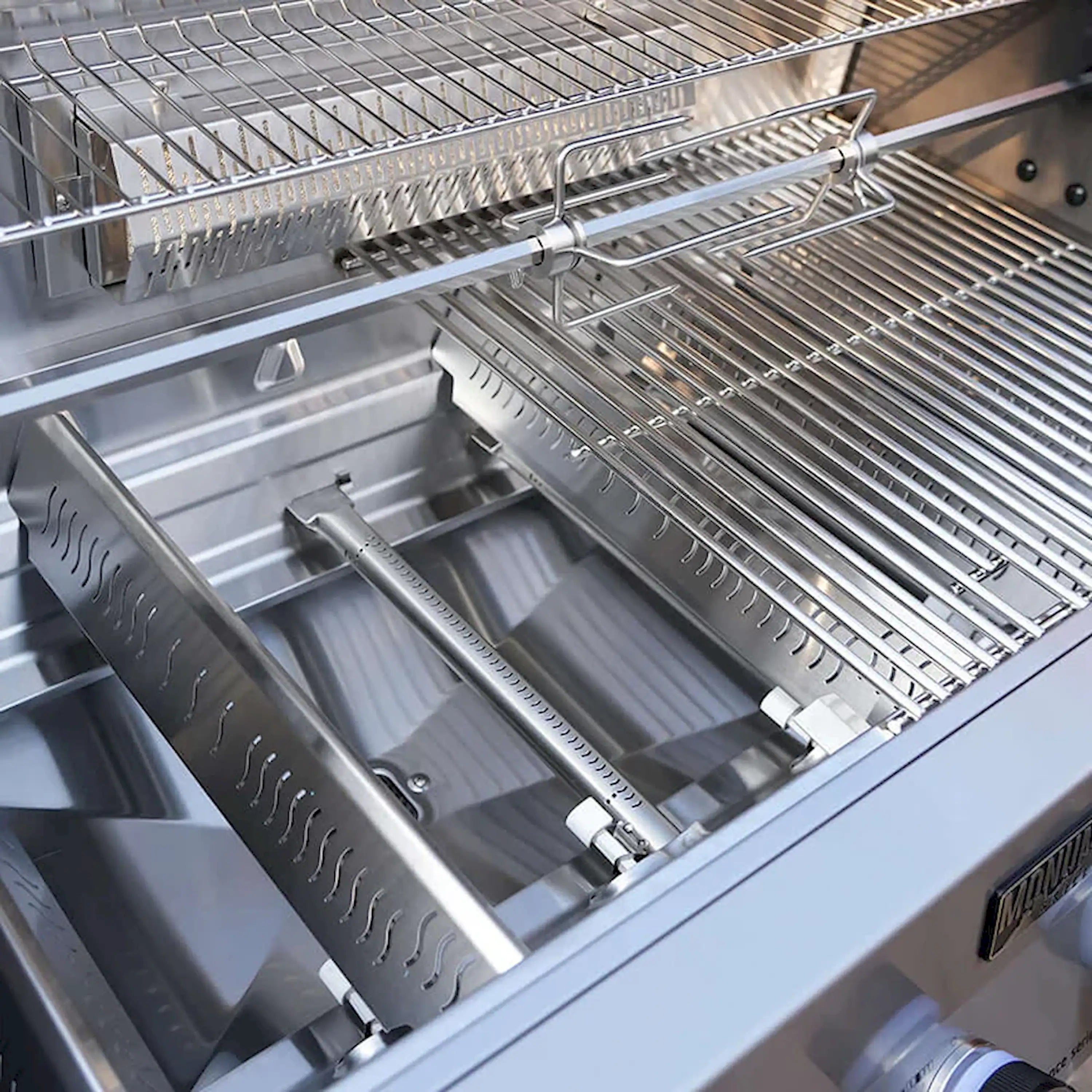 Stainless steel gas grill interior with heat shields, burners, and grates