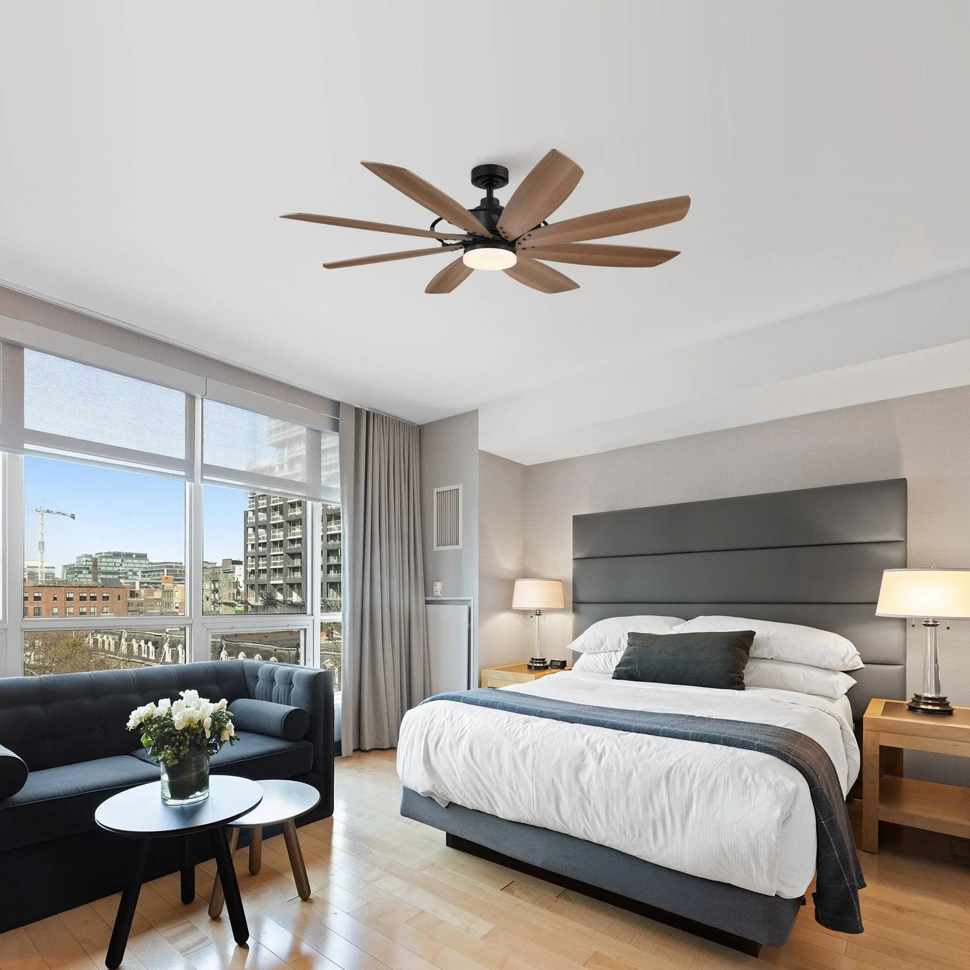 Ceiling fan with black housing, tan wood blades, and white globe light mounted on ceiling.