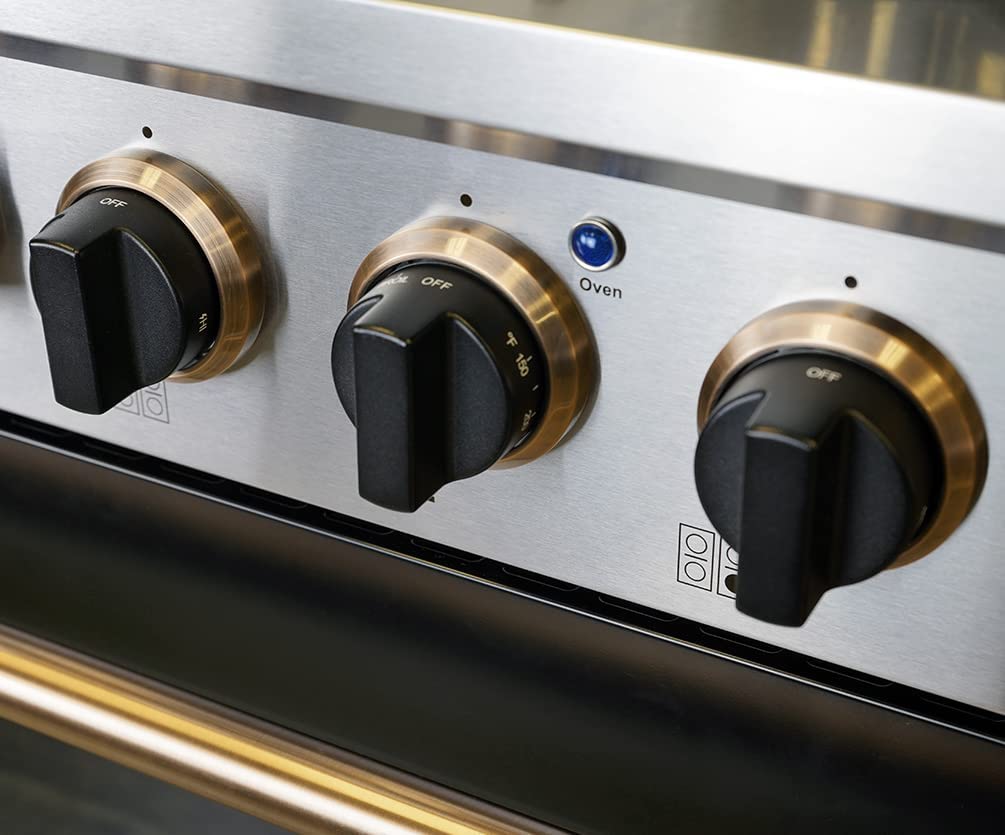 Close-up of black range knobs with gold trim on a black control panel