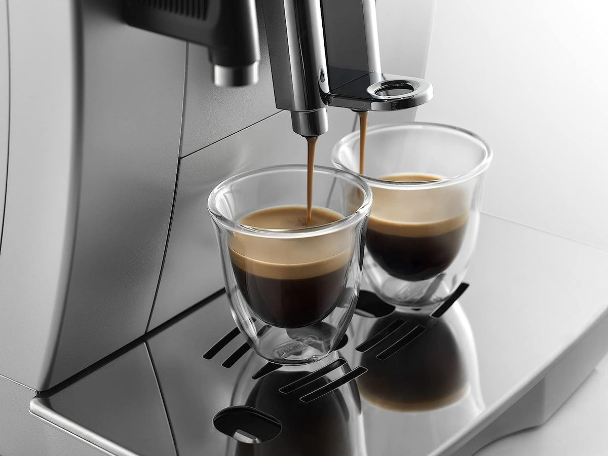 Two clear espresso glasses under an espresso spout, being filled